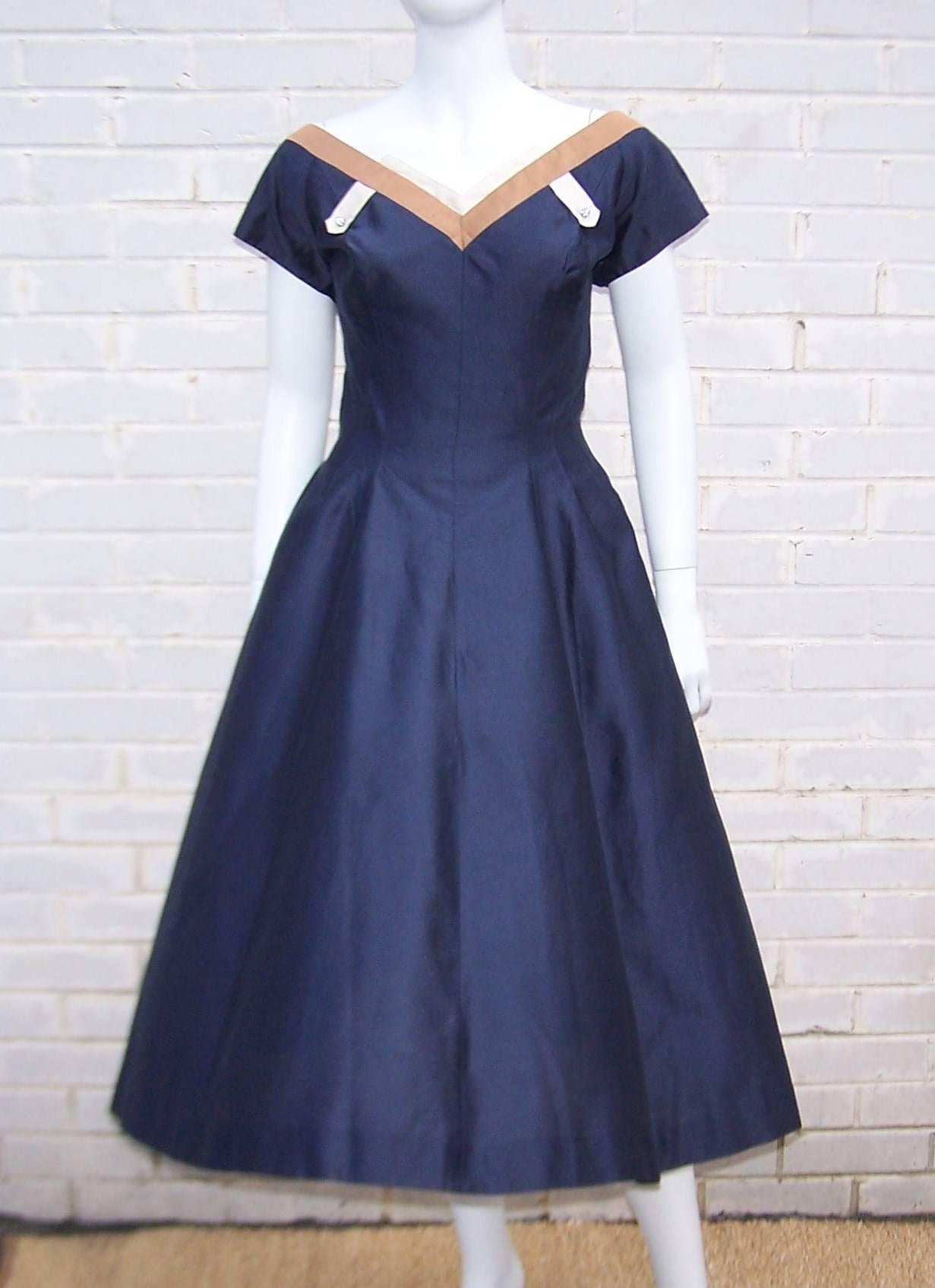 Combine a 1950's feminine silhouette and contrasting graphic details and you have a party dress perfect for a modern day wardrobe.    The weighty polished navy blue fabric provides volume to the full circle skirt while the tan and ivory trim