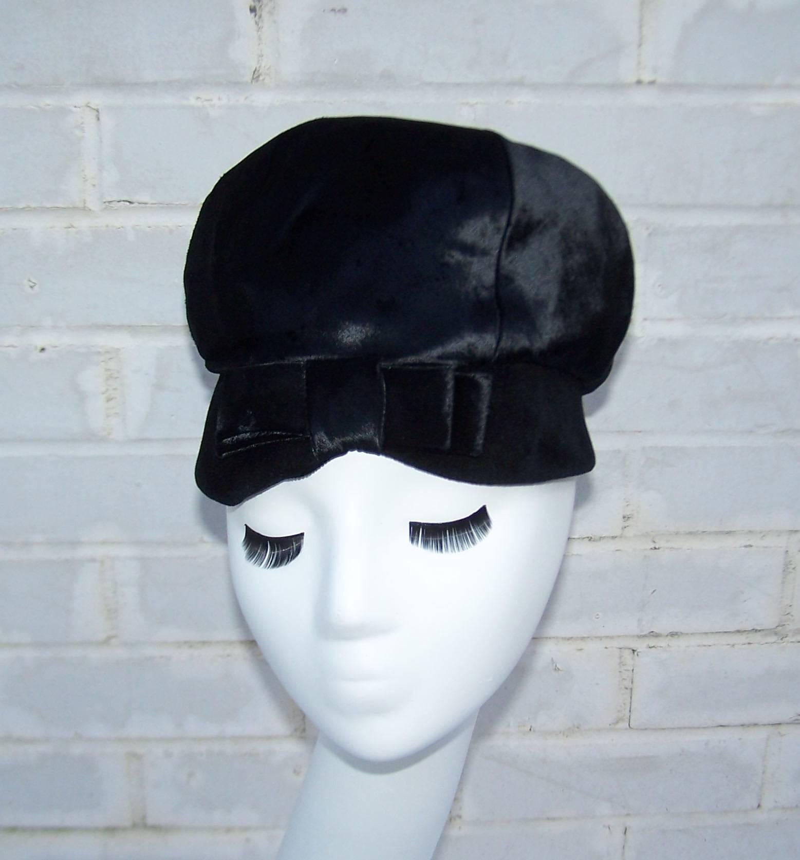 This adorable hat designed by John Harberger for his millinery line, Mr. John Jr., has a 1960's period perfect mod aesthetic.  The body of the hat is a flat velvet that has the feel and appearance of pony hide.  The face framing brim is a soft
