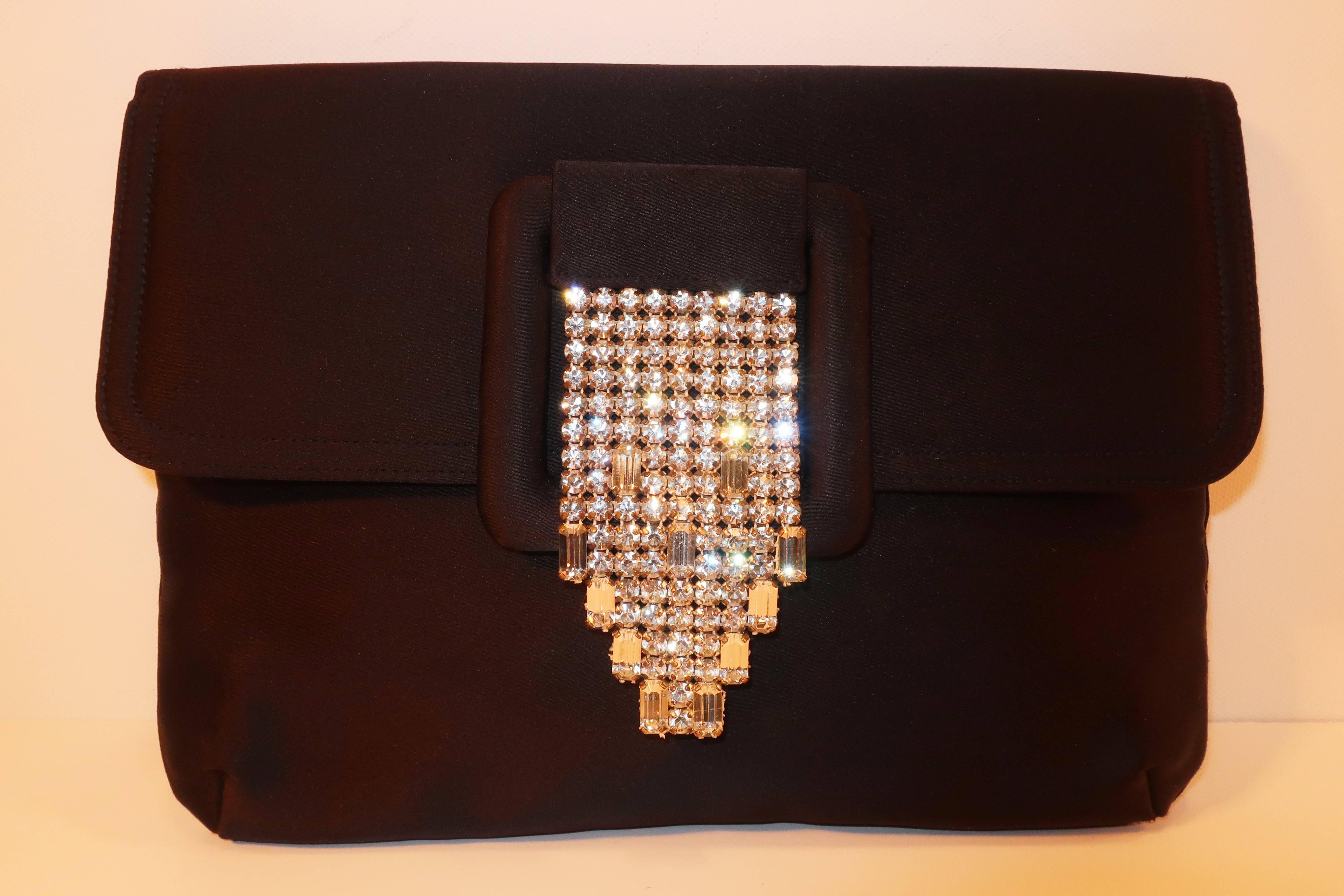 This Art Deco style clutch handbag from Morris Moskowitz will take a simple evening look from functional to fabulous.  The envelope shaped black peau de soie silhouette is accented with a sparkly rhinestone waterfall buckle with a snap closure.  The