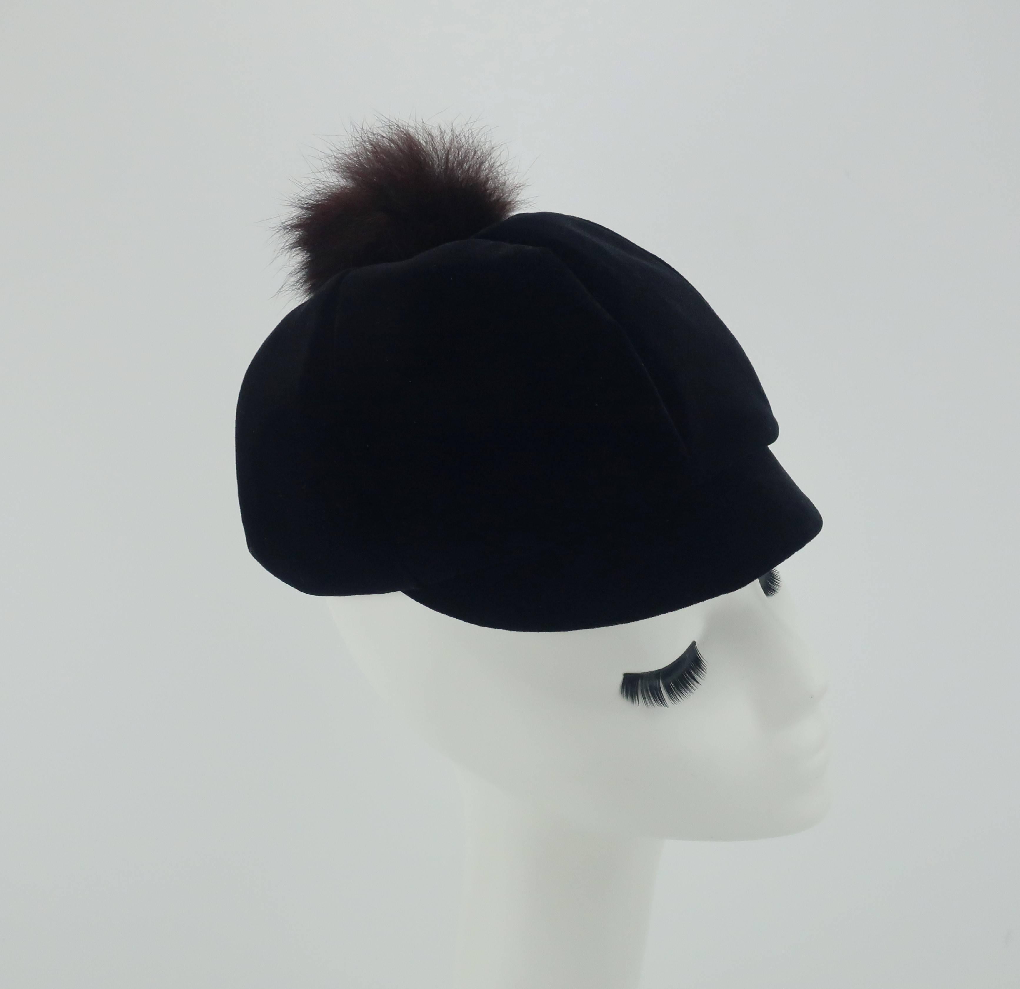 This black velvet cap is a 1960's period perfect silhouette for a mod style.  The skull hugging cap has a short brim and a whimsical dark brown fur pom at the center crown.  The style provides a little warmth and a whole lotta look!  Excellent