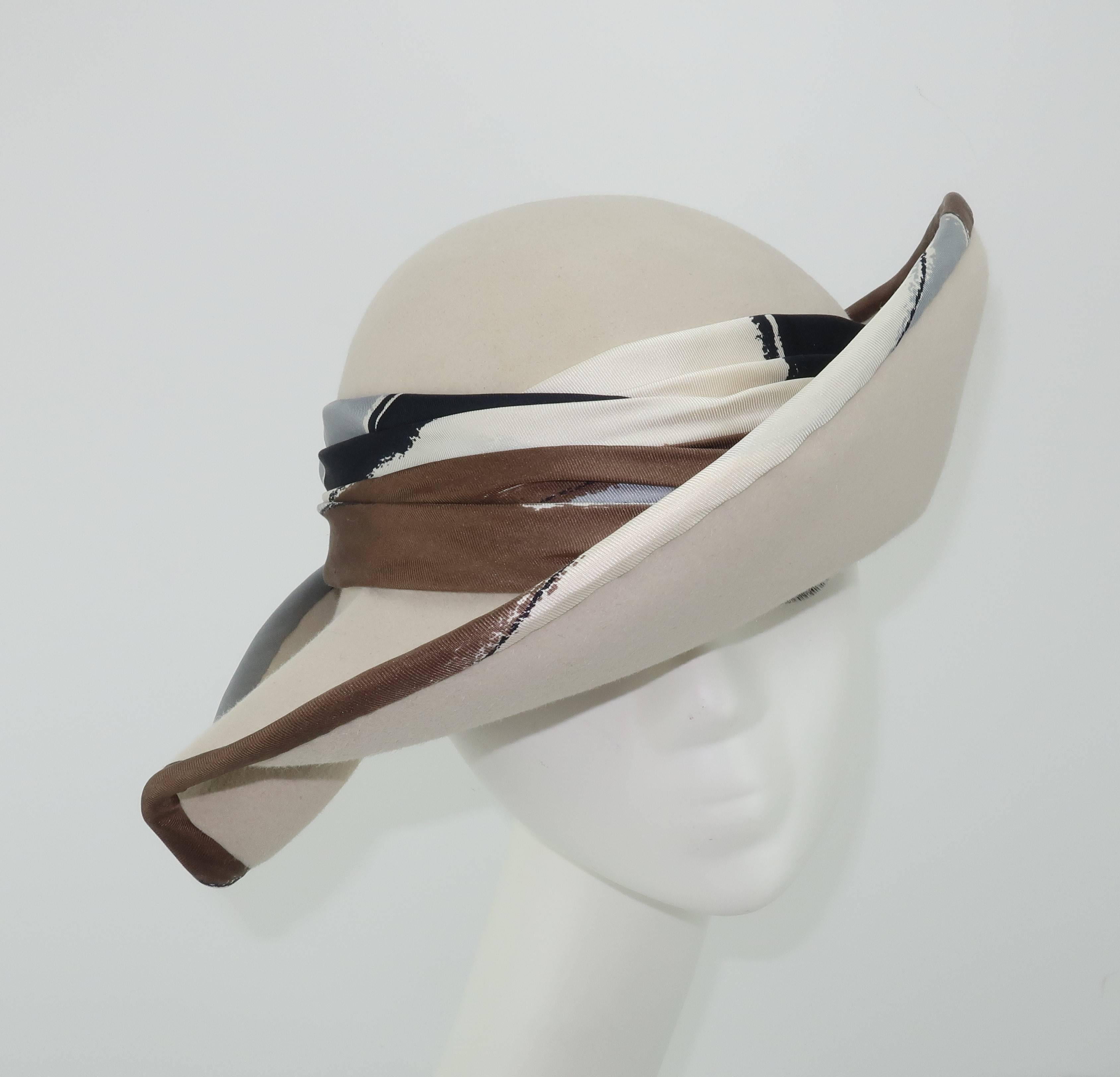 This C.1970 Bonta Creatrice wool felt hat stylishly performs the double duty of providing an incognito brim for hiding and yet a beautiful frame for the face.  The bone colored Italian wool felt body is expertly shaped with asymmetrical folds