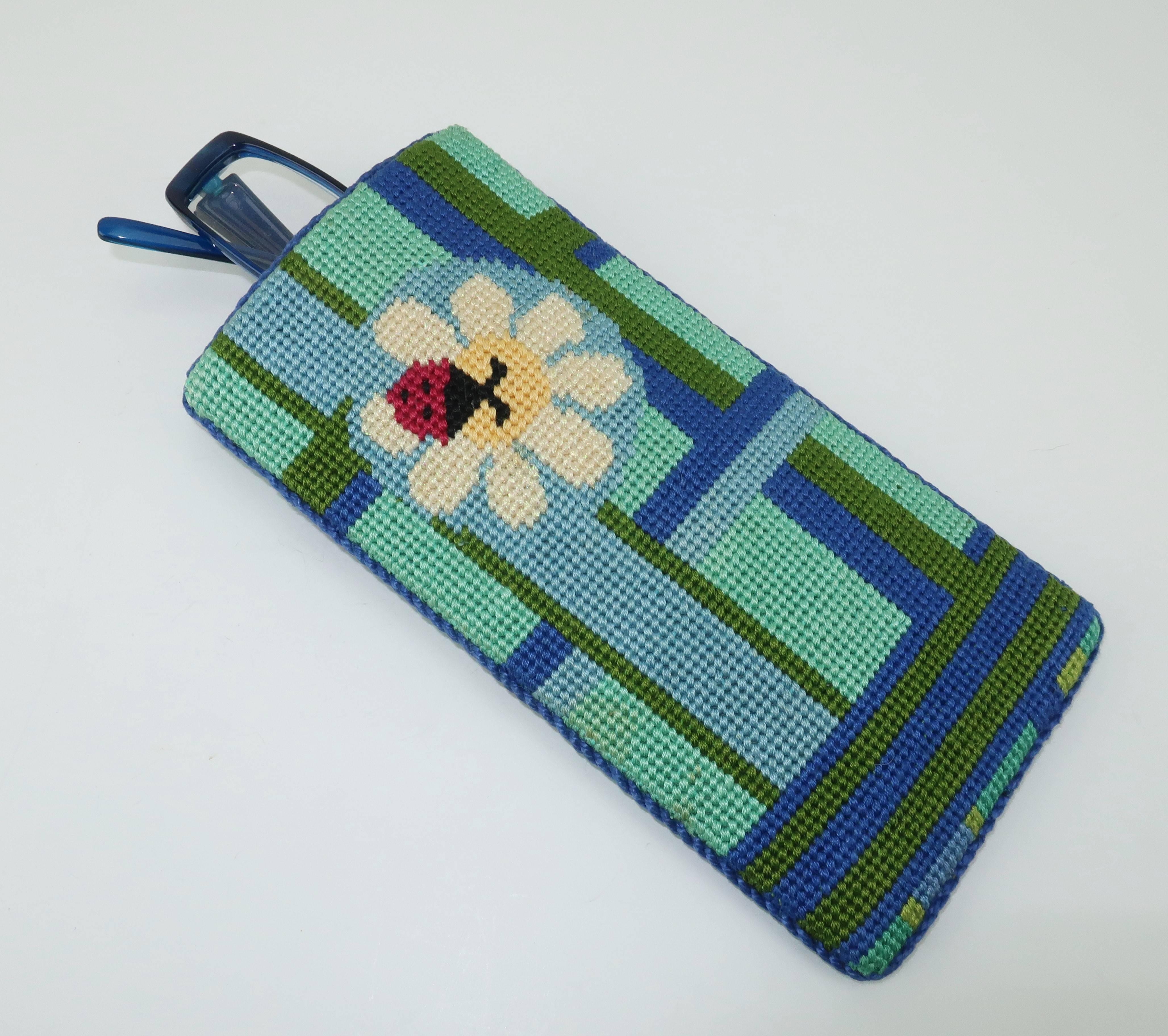 This lucky little ladybug has landed on a wonderfully graphic blue, green and turquoise needlepoint eyeglasses case.  Both sides are fully decorated with pearly metallic threading on the flowers and blue silk cording on the edges.  The inside is