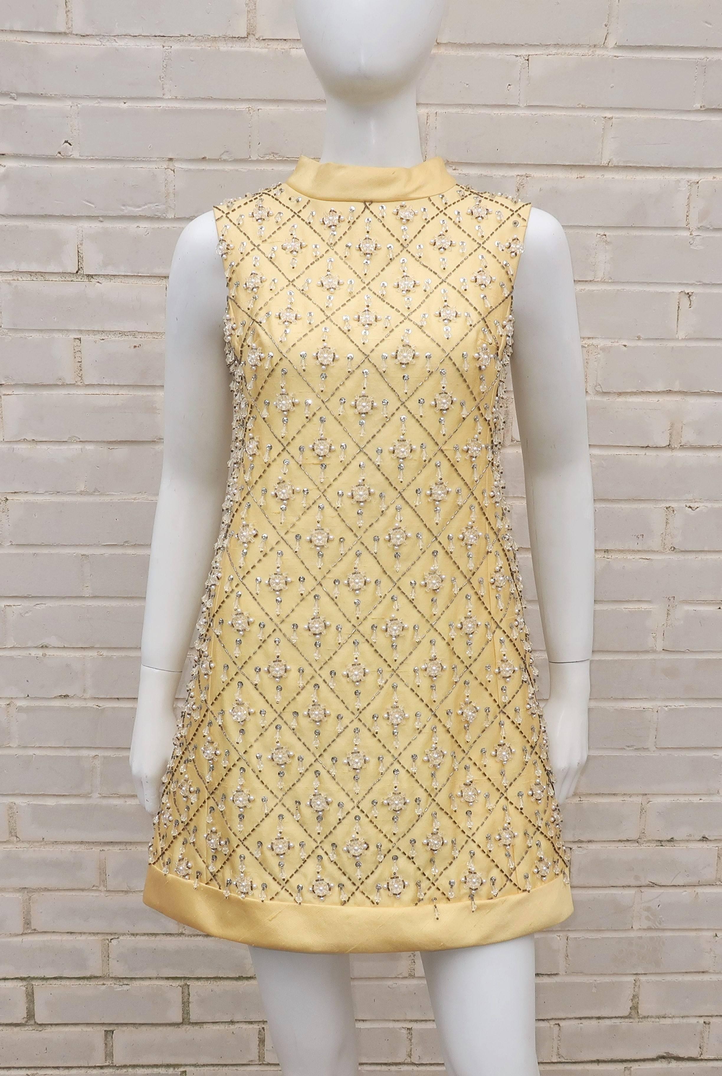 Get your go-go on with this 1960's Gino Charles mini dress.  The buttery yellow dupioni silk is a shift style silhouette which zips and hooks at the back.  The mock turtleneck and hem are banded to create a frame for the silvery beaded lattice