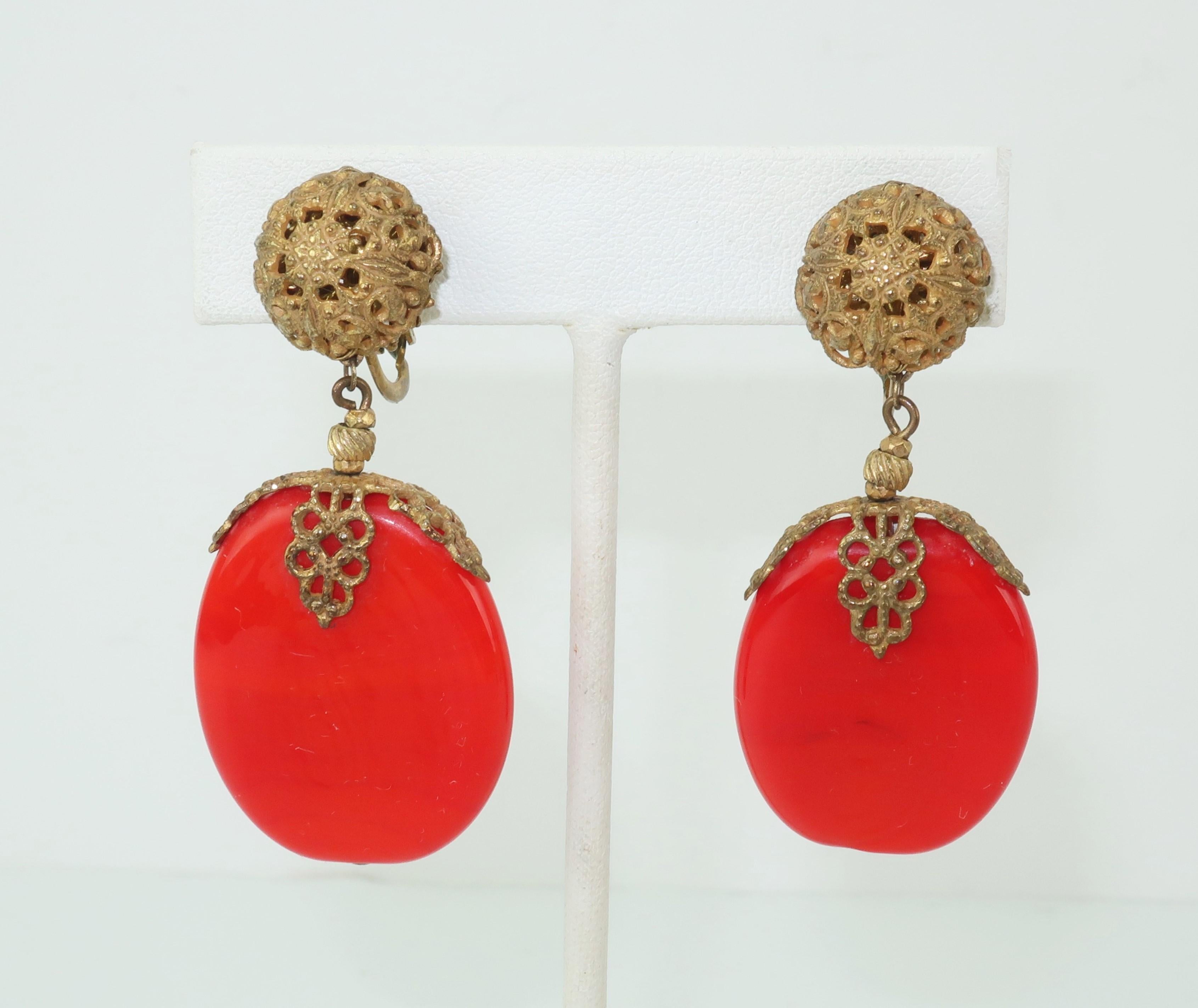 This 1950's Miriam Haskell demi parure, consisting of a brooch and dangle earrings, is reminiscent of 1920's Art Deco jewelry with an exotic aesthetic...imagine opium den chic and you have the picture.  The set is created from a fiery red glass