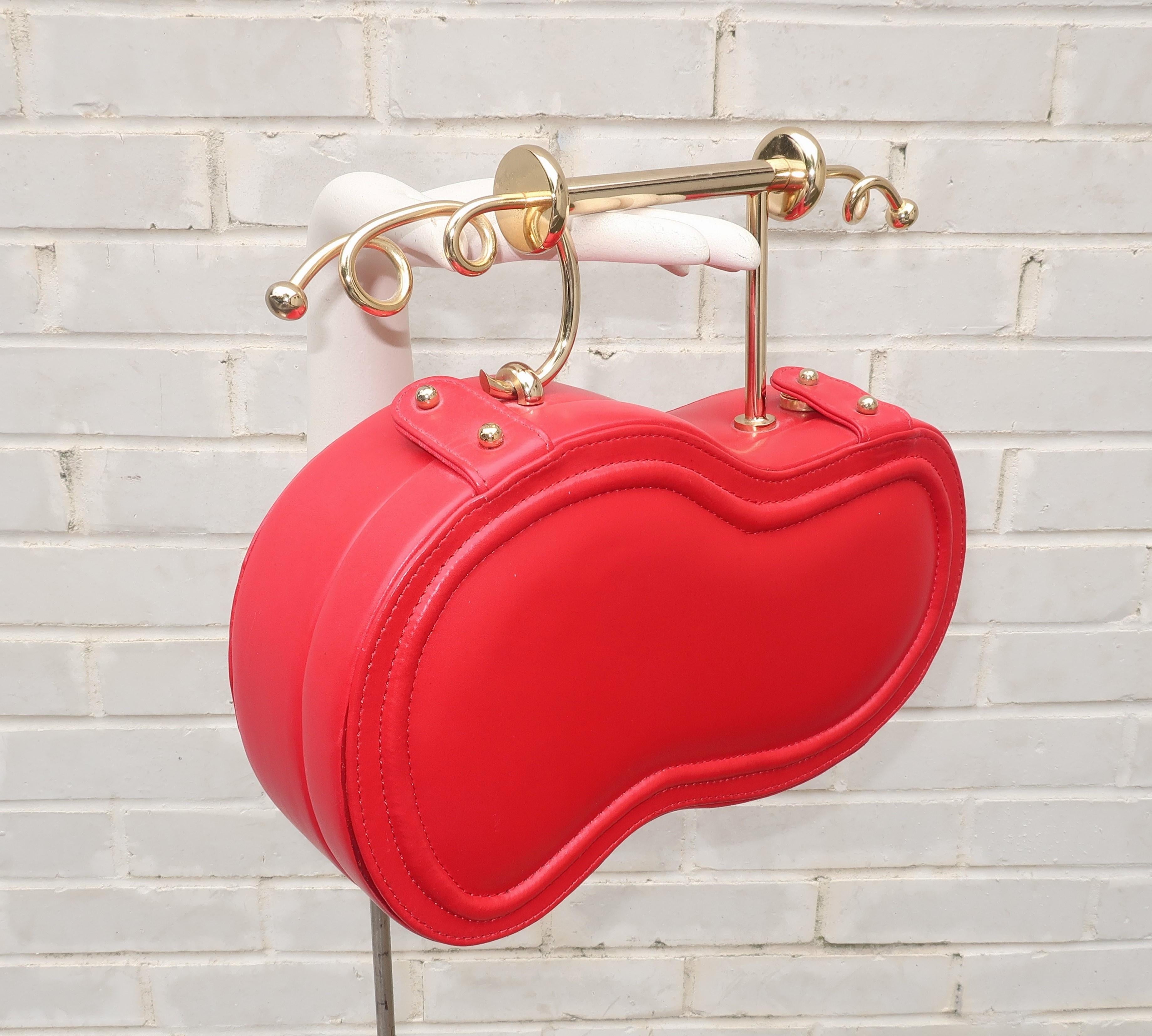 This red leather Italian handbag definitely puts the fun into fashion with both a unique silhouette and a sensationally surreal handle.  The shape is somewhat reminiscent of a violin case with a Salvador Dali-esque gold tone handle featuring scrolls