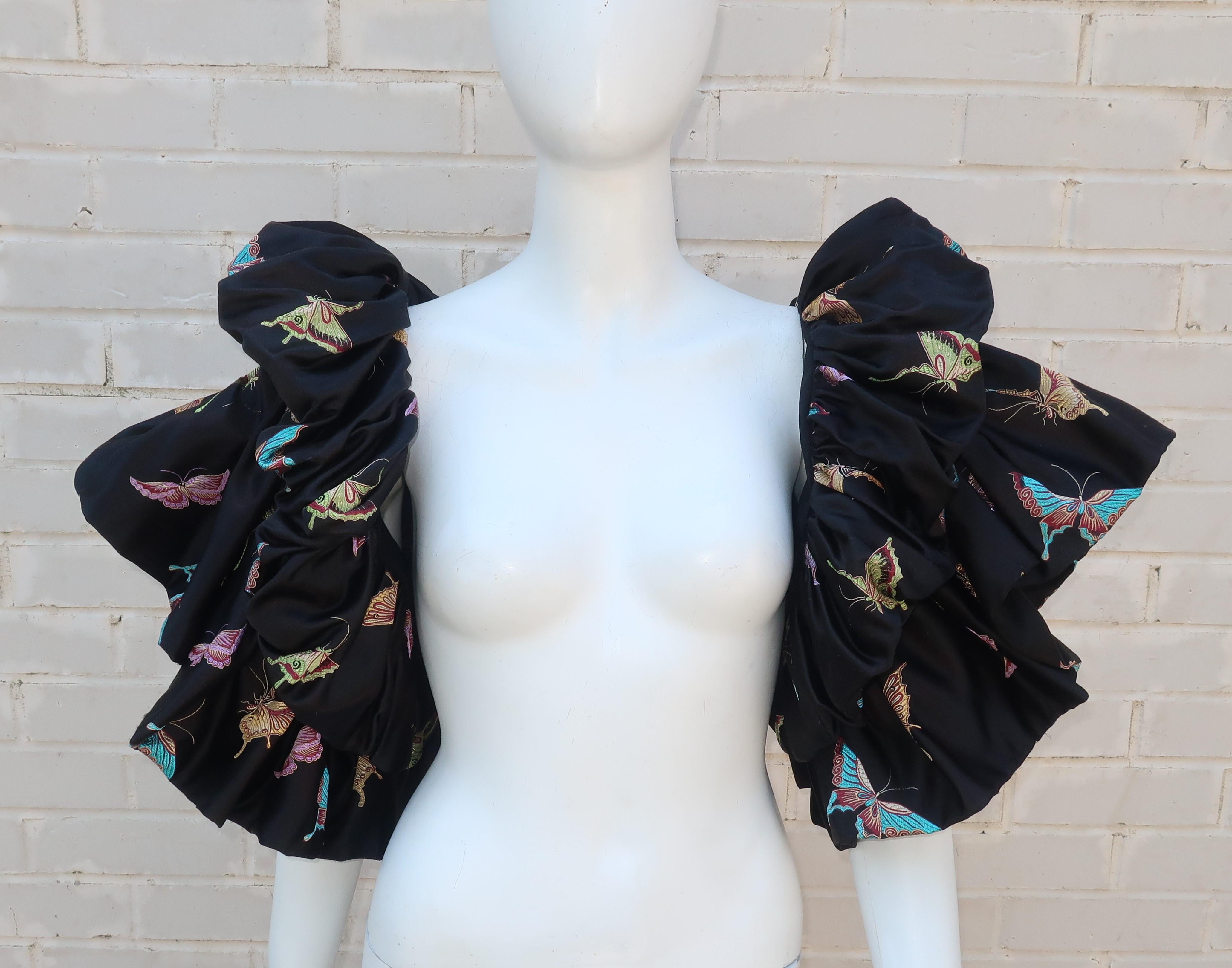 The metamorphosis of simple evening wear to its full dramatic potential is easily accomplished by adding this black satin brocade shrug beautifully decorated with butterflies.  The shrug is constructed with multiple layers of pleated fabric anchored