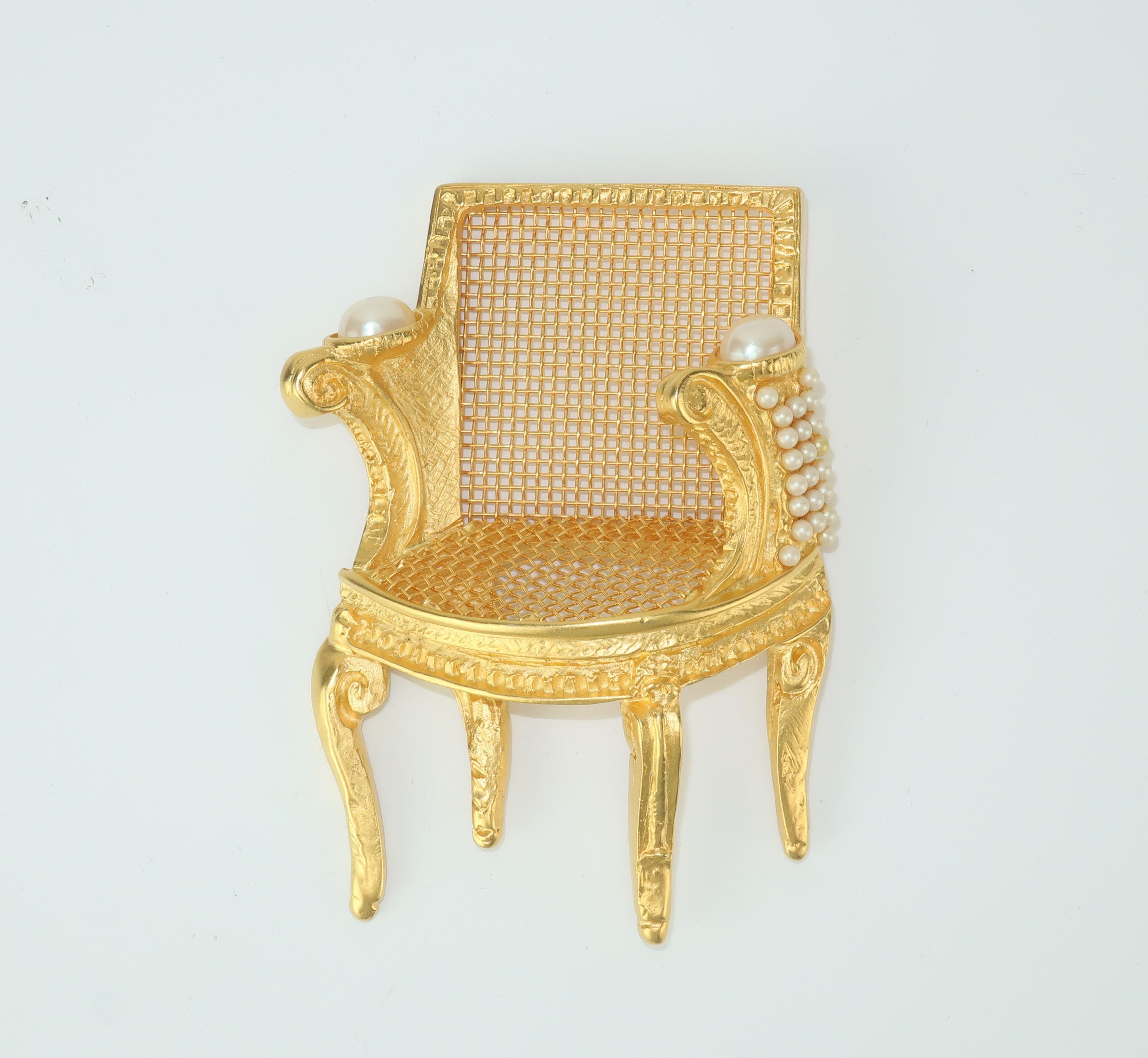 Get your seat at the table in grand style with this fun and fabulous Karl Lagerfeld chair brooch.  The 3-D French bergère style chair is highly detailed in a matte gilt gold metal accented with faux pearls.  The clever open screen back and seat