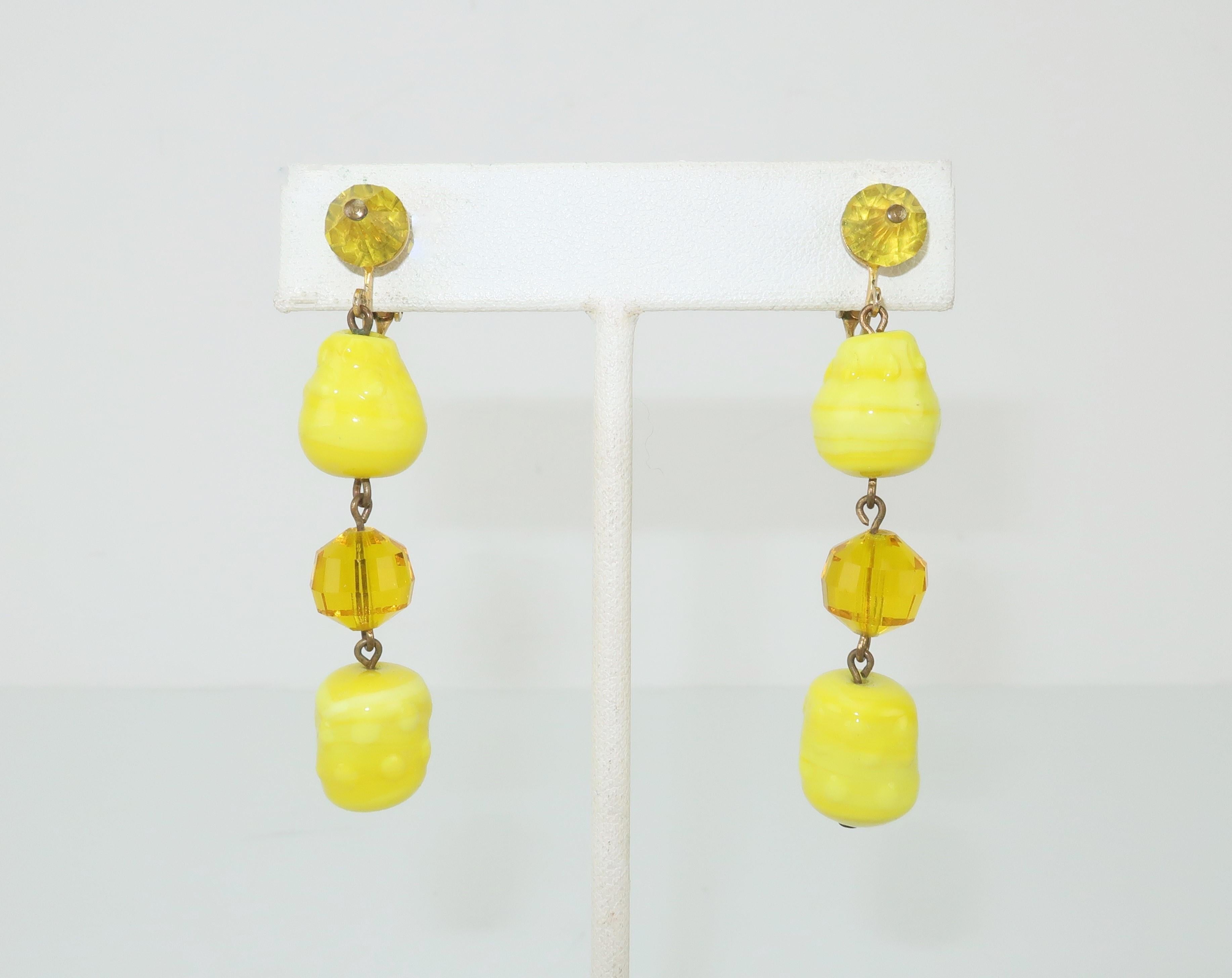 These C.1960 Vogue Jewelry earrings consist of articulated bright yellow and faceted amber glass beads with comfortable clip on hardware.  The dangling movement and pop color are period perfect details for adding a fun sixties vibe to your look. 