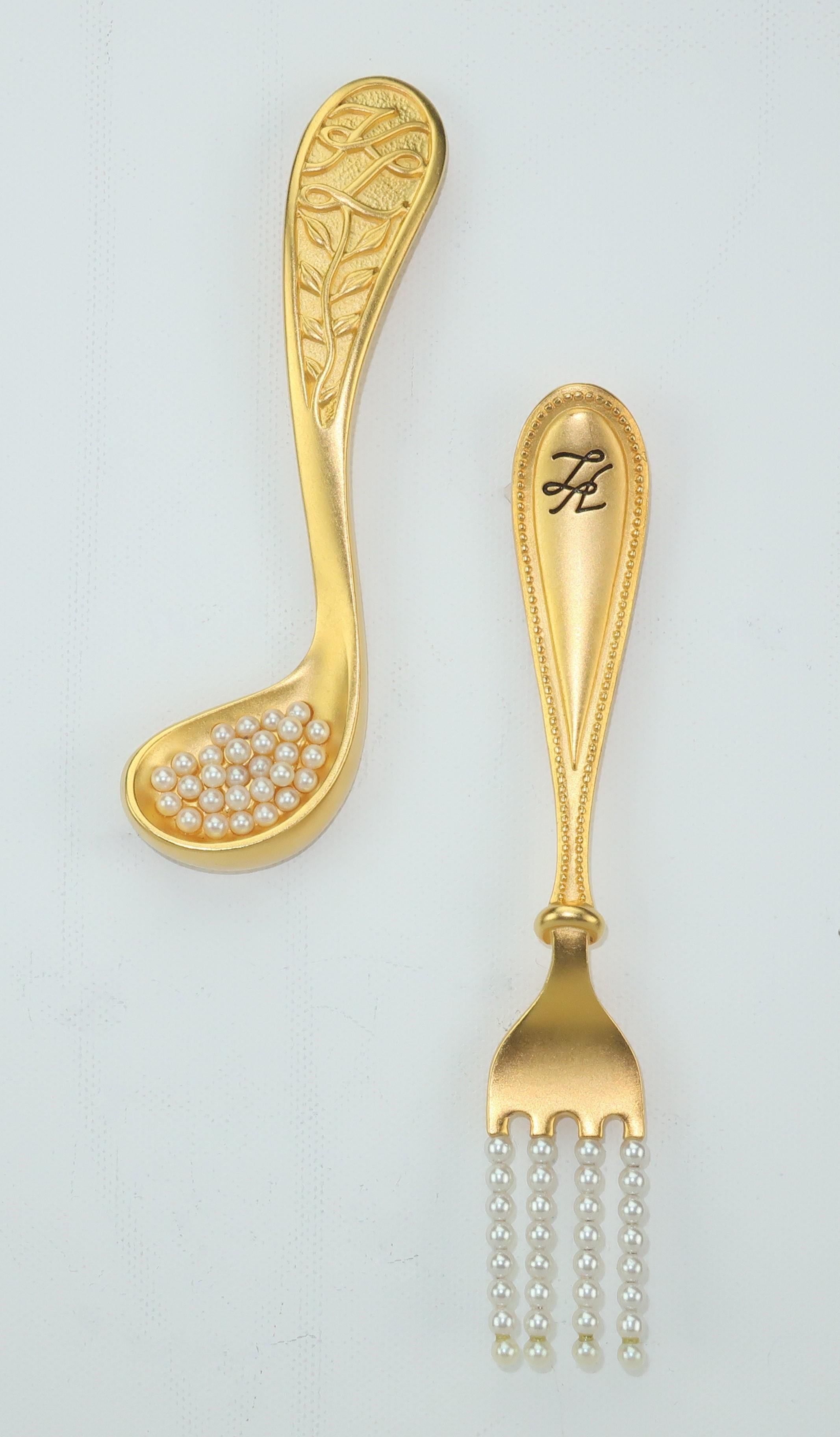 Karl Lagerfeld creates a culinary delight with this whimsical pair of fork and spoon brushed gold tone brooches embellished with pearl beads.  Each large brooch is outfitted with a straight pin, safety clasps and signatures on the front and back. 