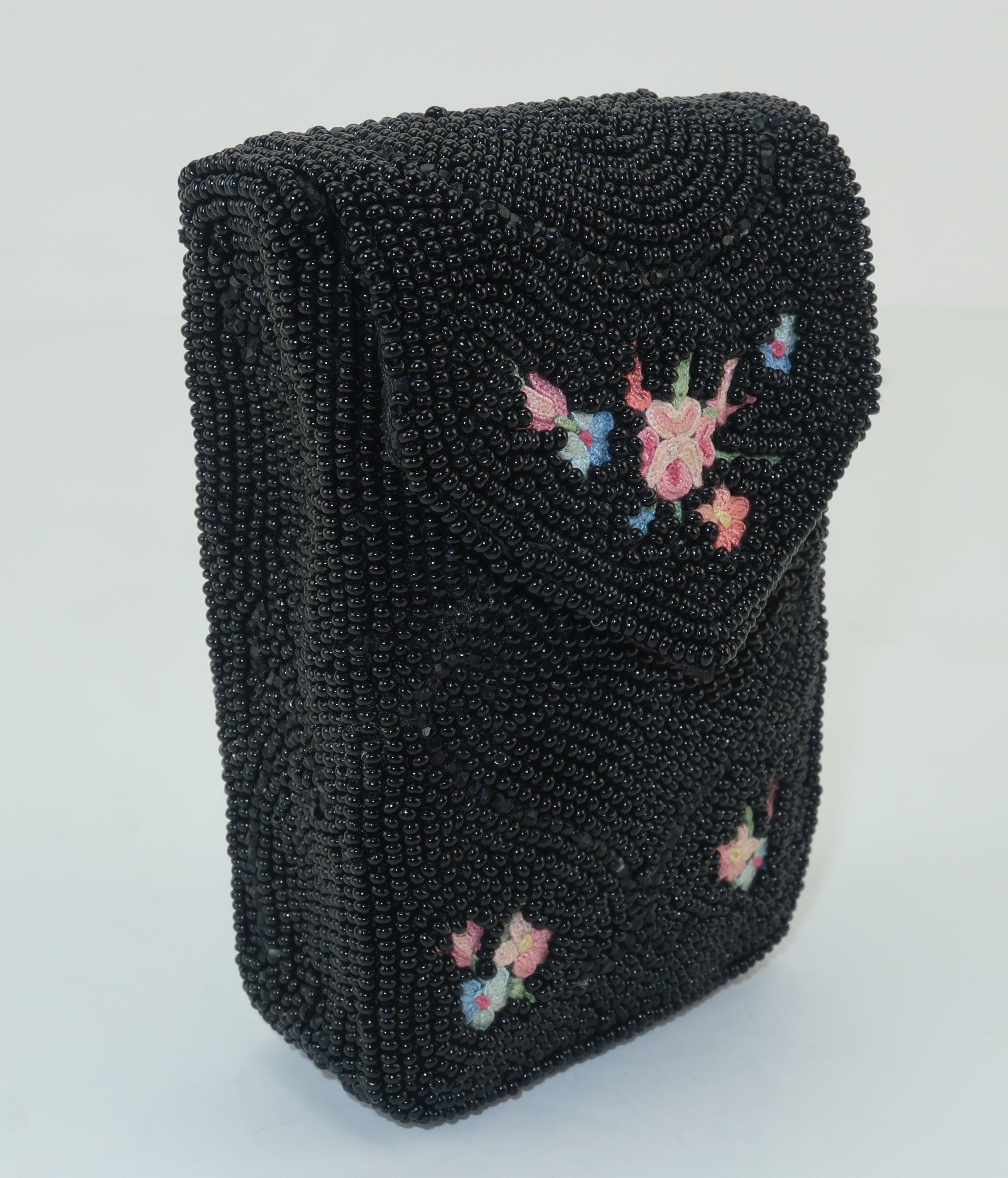 This ultra feminine 1950’s French black seed beaded cigarette case is detailed with a bright floral chain stitch pattern in shades of pink, yellow, blue and green.  The front flap opens with a snap and the interior is lined with black satin. 