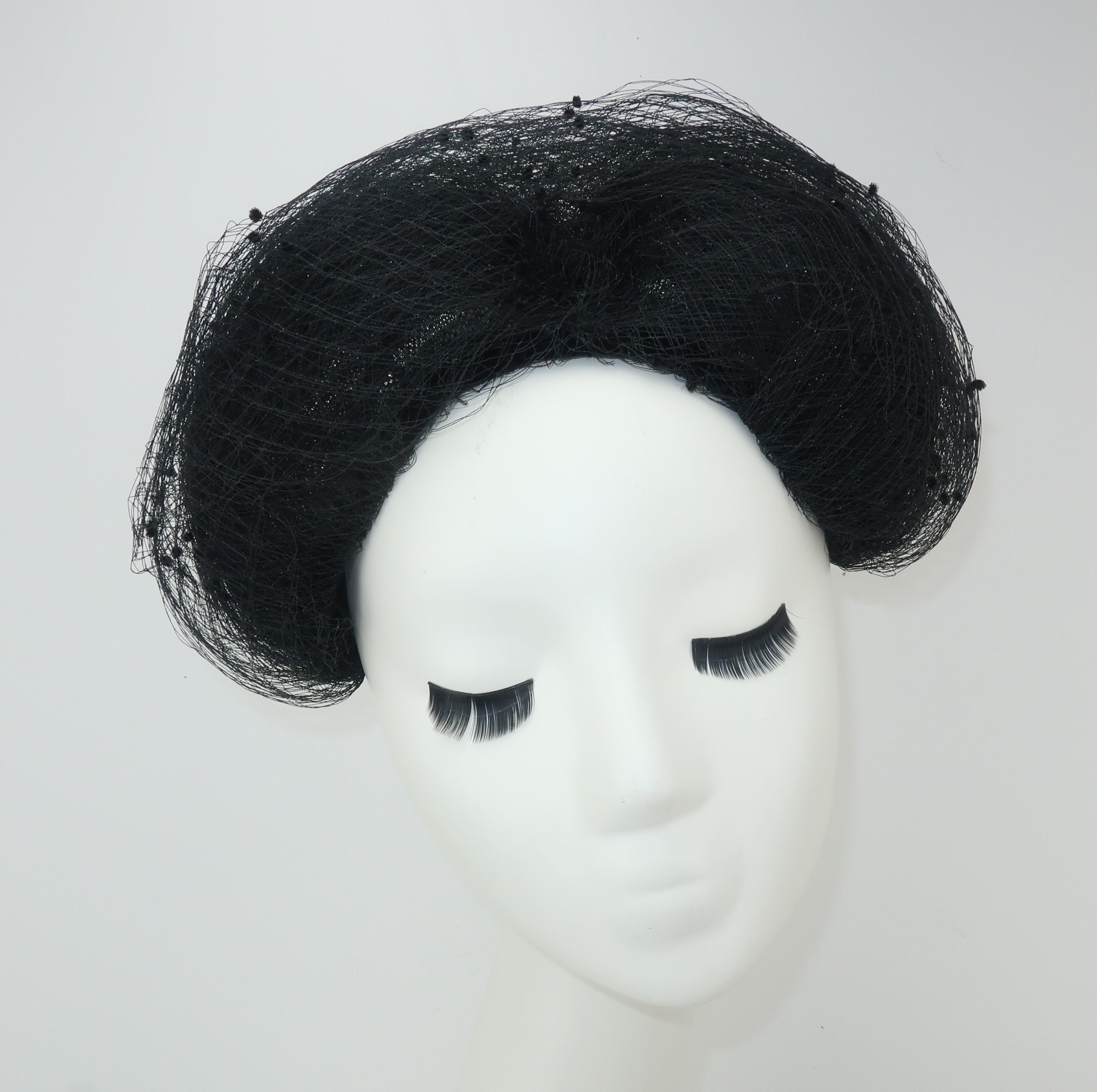 You will have loads of fun with this C.1950 fascinator hat constructed with a black wired net armature and embellished with swirls of swiss dot netting.  The unusual shape conjures up images of everything from a Geisha wig to a matador's hat and