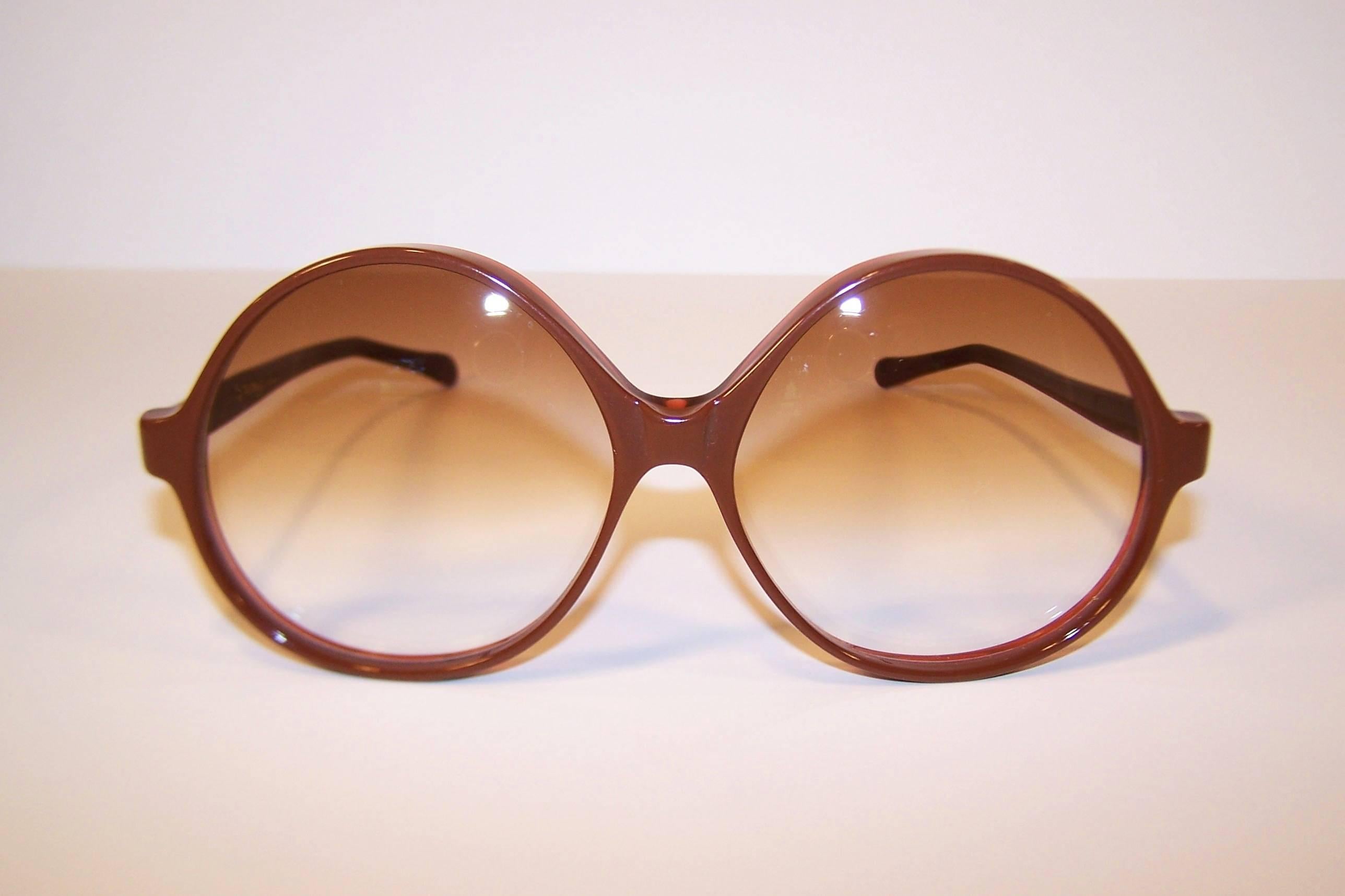 Supersize me!  These large framed Renauld sunglasses are a chocolate brown with a transparent orange backing.  They sport gradient lenses with a modified ovoid shape.  Renauld was a fashion forward French sunglasses company manufactured in the