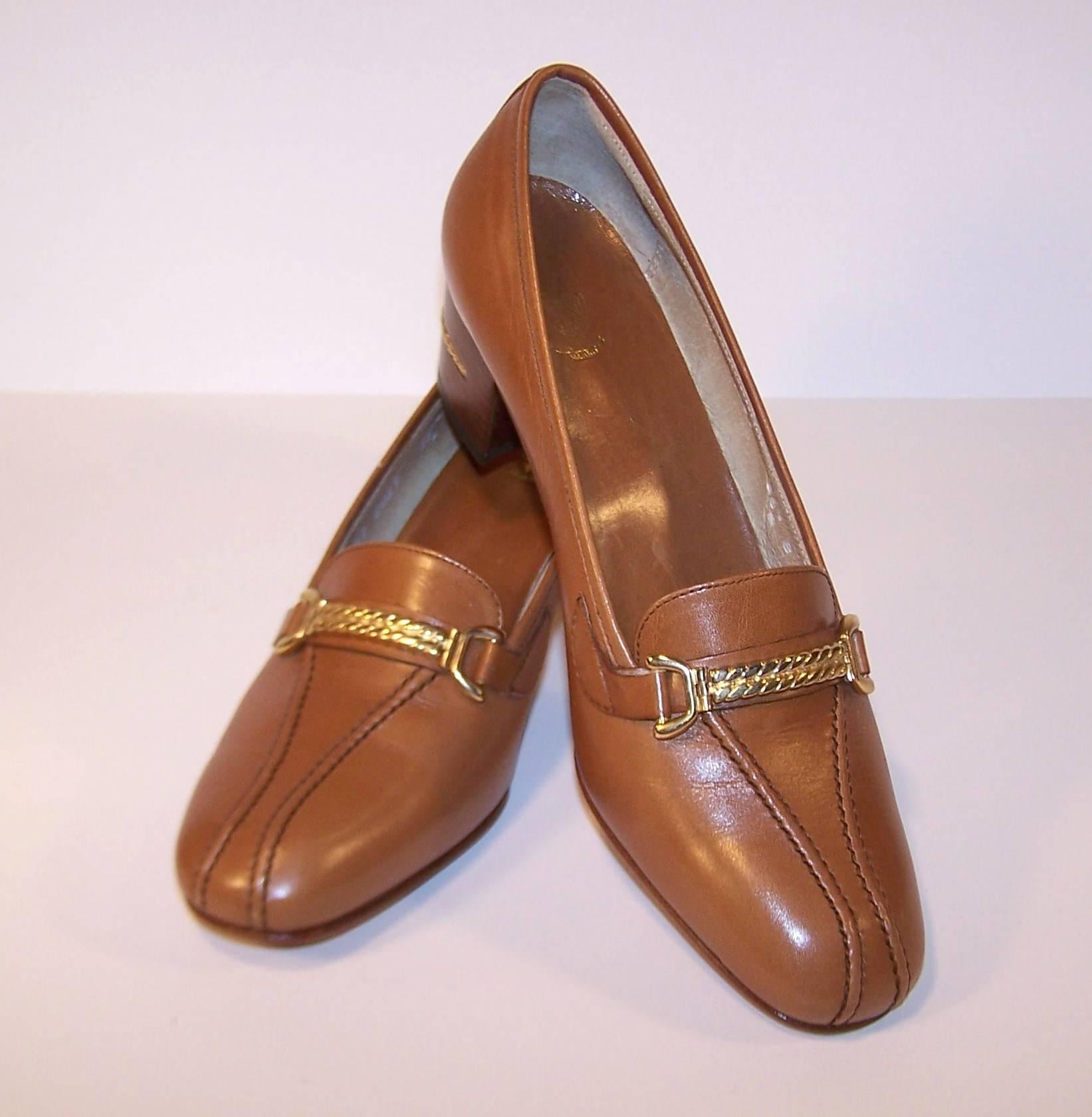 This versatile tan leather Gucci loafer is a classic paired with trousers, skirts or jeans.  The vamp is decorated with gold braiding which is repeated on the 2" tall wooden heels.  They appear to be unworn (maybe tried on a time or two) and