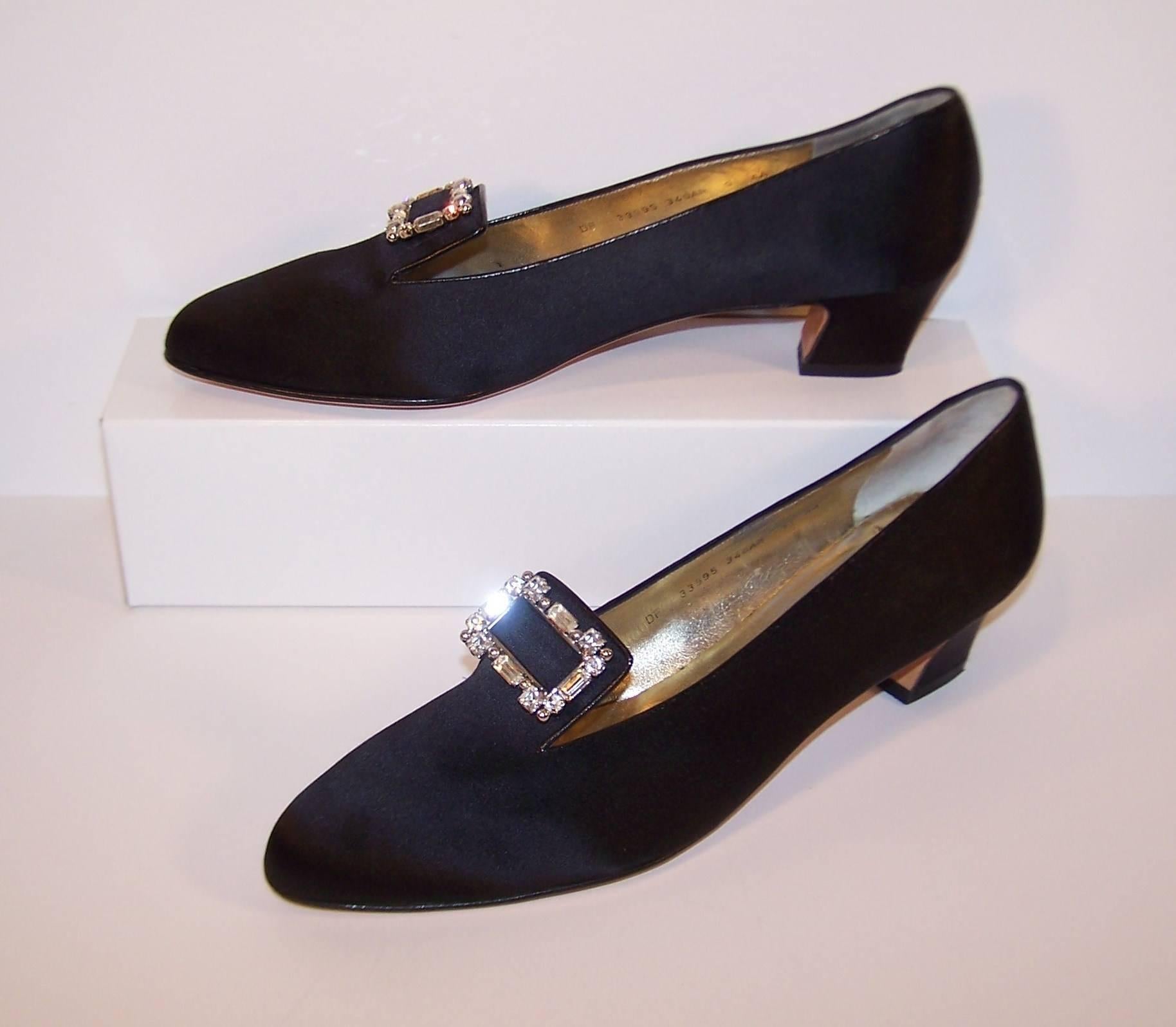 These elegant evening slippers by Ferragamo have all the comfort of modern footwear with the rich details of Edwardian style.  The black satin body is trimmed in black leather and sports square rhinestone and stud encrusted buckles.  The 2"