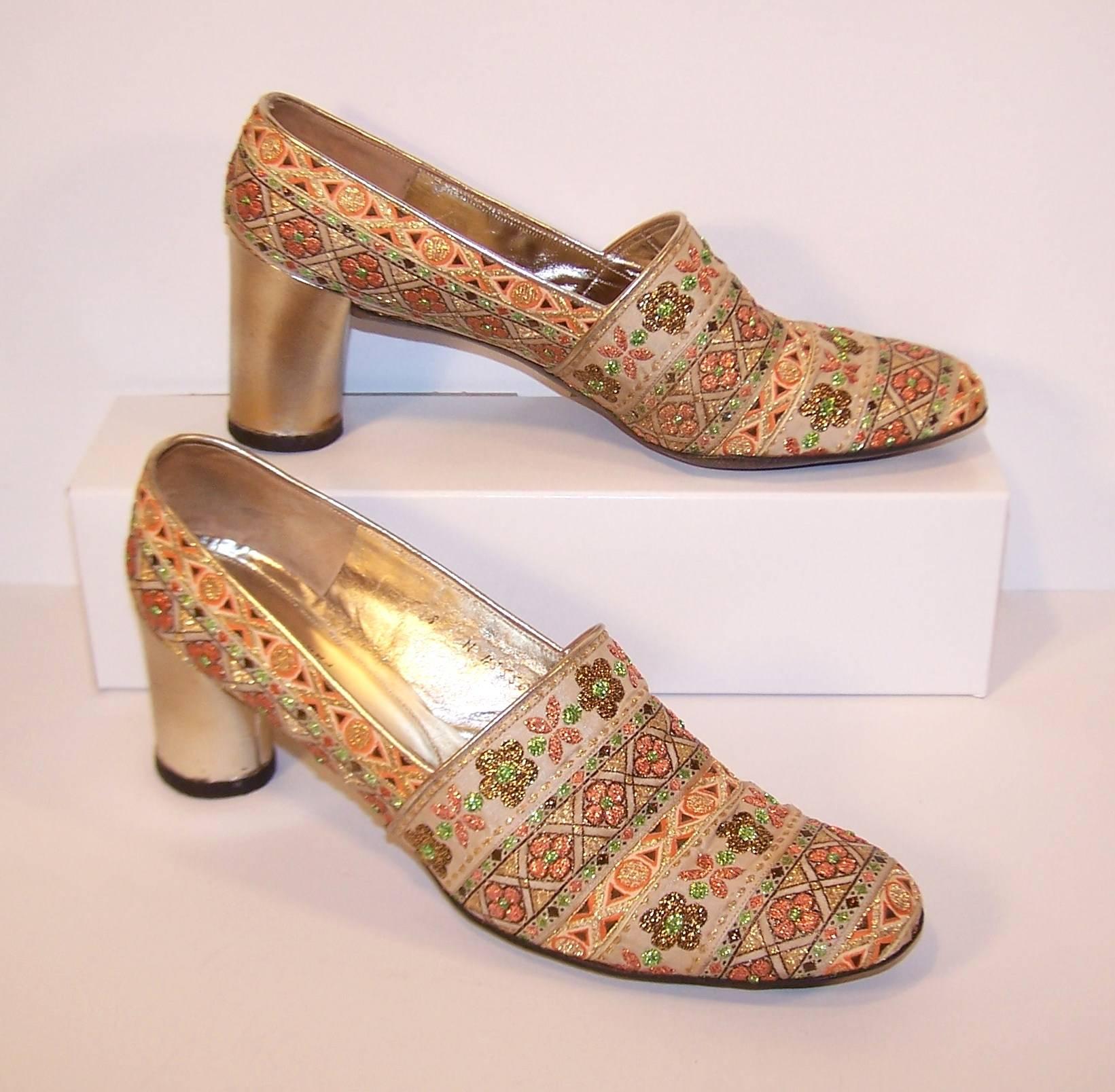 Put your most dazzling foot forward with 1960's Charles Jourdan exotic inspired brocade fabric shoes.  The metallic fabric is a graphic floral design in brown, gold and copper colors edged in gold leather with comfortable 2.75