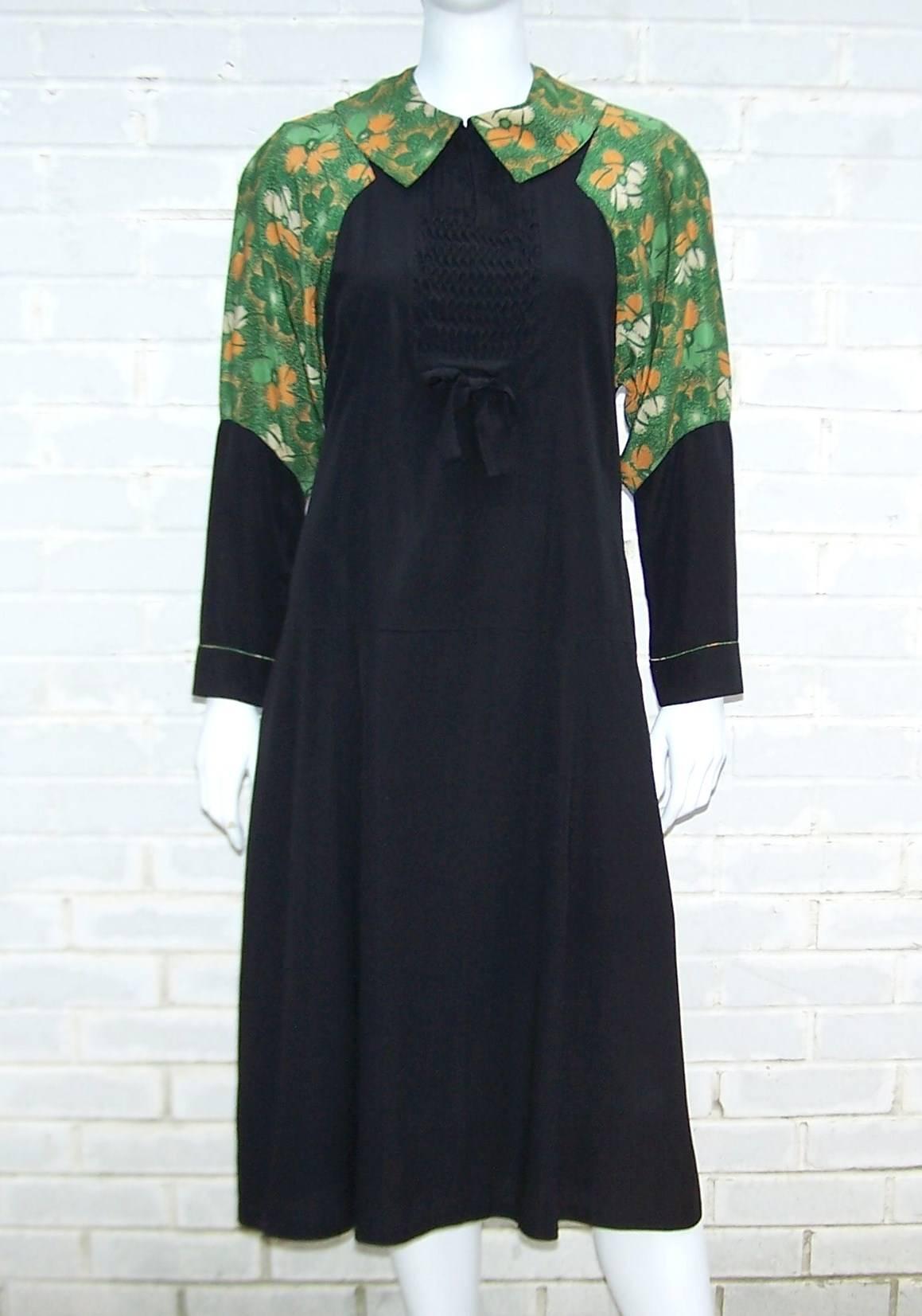 The unique design on this 1920's dress creates a faux visual of an apron or pinafore style dress.  The black rayon contrasts nicely with the bright green abstract floral pattern and the intricate pin tucking and bow provide visual interest.  The