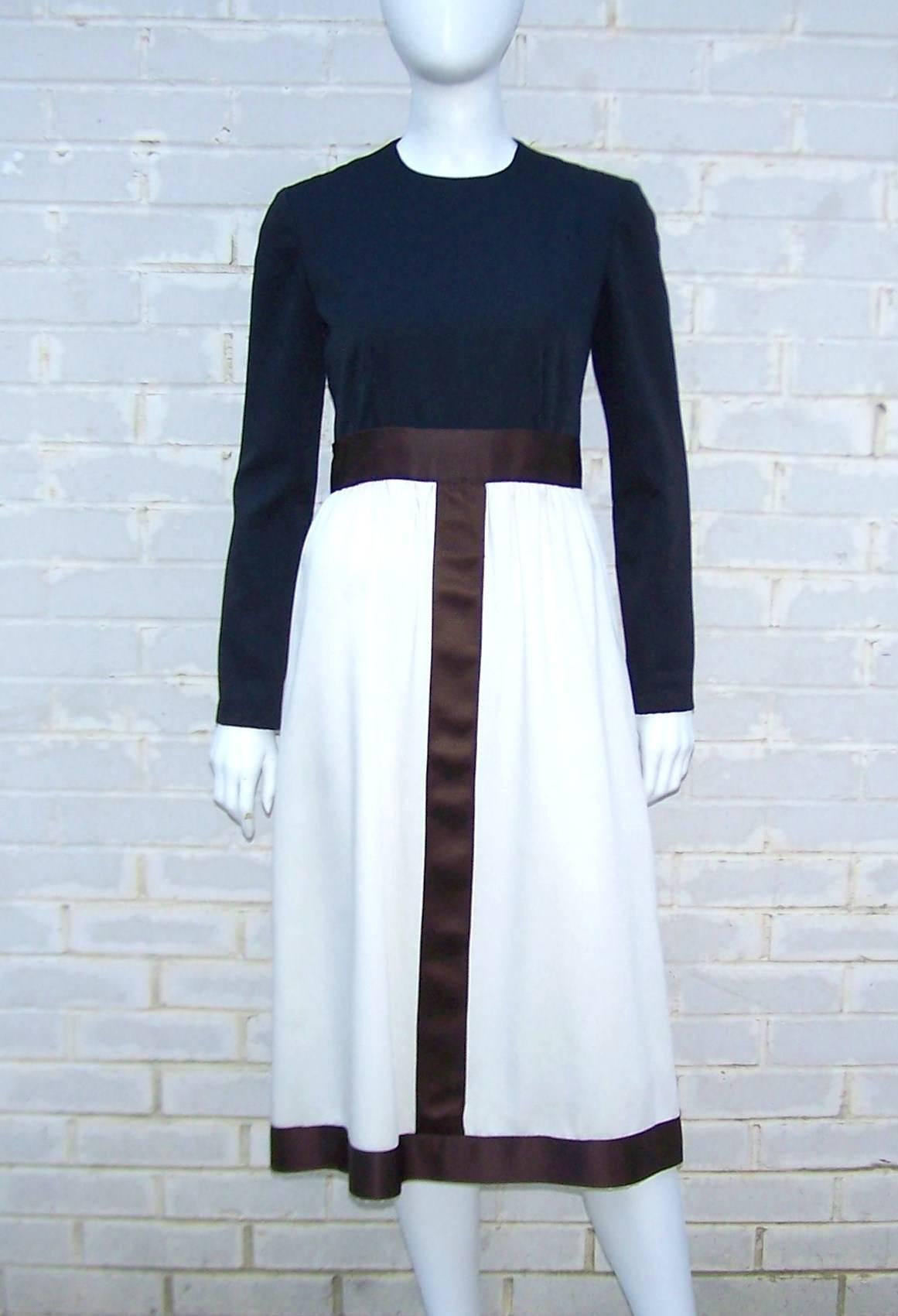 This classy dress is made by Rodrigues for Peter Clements.  The bodice is a form-fitting black satin which is paired with a winter white skirt offset by dark brown satin ribbon.  The color block effect is eye catching and gives the traditional