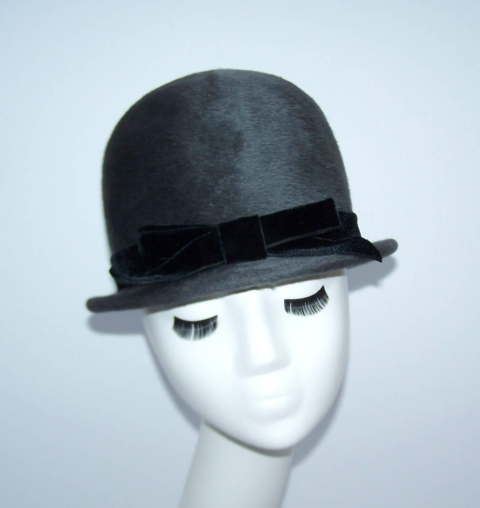 This adorable 1960's charcoal gray wool hat is reminiscent of the helmet worn by London bobbies...with a definitive feminine twist, of course!  The quality Italian made body is adorned with a black velvet bow.  Add a military inspired jacket to