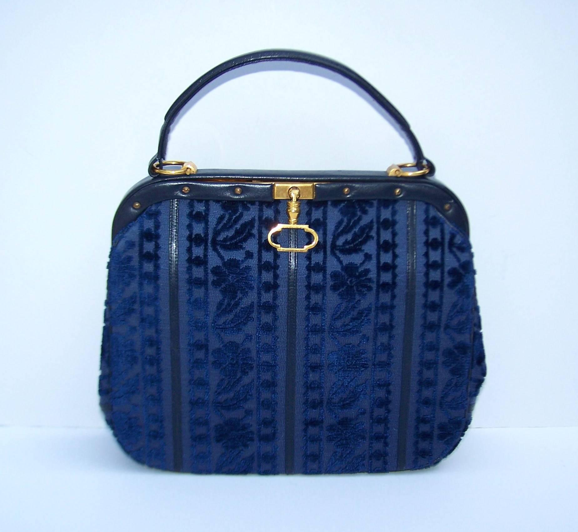 Giuliana Camerino's designs are precious baubles and the perfect fashion accessory.  This beautiful blue cut velvet handbag is trimmed in leather with a leather handle and gold metal hardware.  The leather interior features one zippered pocket and