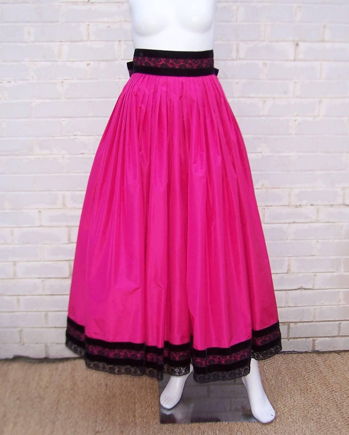 This Miss O by Oscar de la Renta design is fun and girlish with a good dose of beautiful opulence.  A ballroom style full skirt of bright fuchsia silk taffeta is trimmed in black velvet and lace at the waist and hem with a bow at the back to wrap