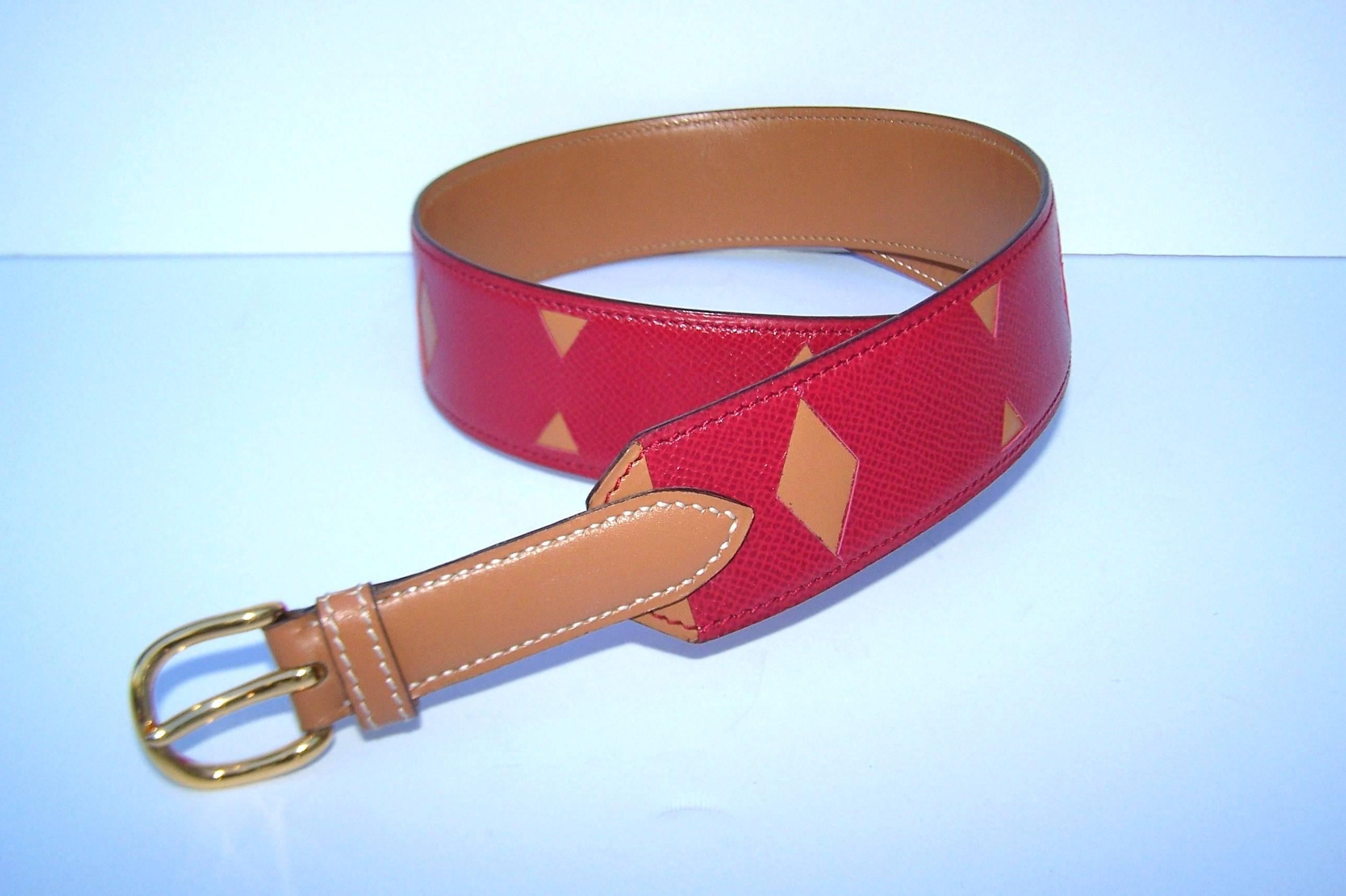 A classic with a twist!  Hermes has created a fun two tone belt by layering a camel leather (Hermes 'Gold') with red (Hermes 'Rouge Casaque') calfskin cut work in graphic patterns.  Put it all together with gold metal hardware and voila!  A belt
