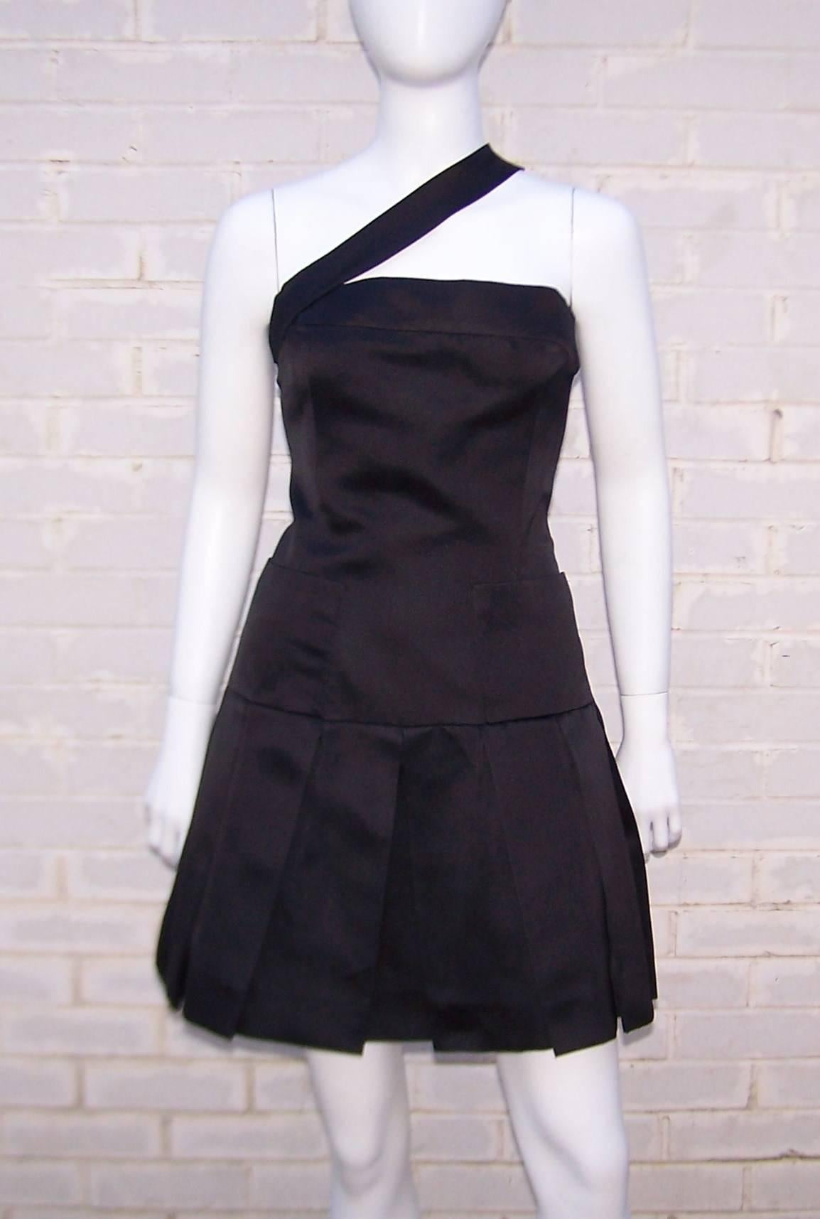 This adorable dress appears to be Chanel's take on a black tie pinafore ... with a good dose of class and style, of course.  The unique design features a wide asymmetrical strap supporting the fitted bodice which yields to a drop waist and box