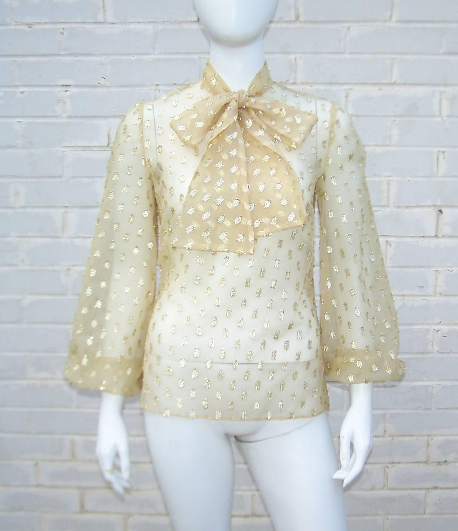 Add a hint of golden glam to any outfit with this sheer lame dotted blouse.  The blouse zips and hooks at the back with a built-in stock tie which can be worn as a bow or double wrapped like a neck scarf.  The balloon sleeves are elasticized at the