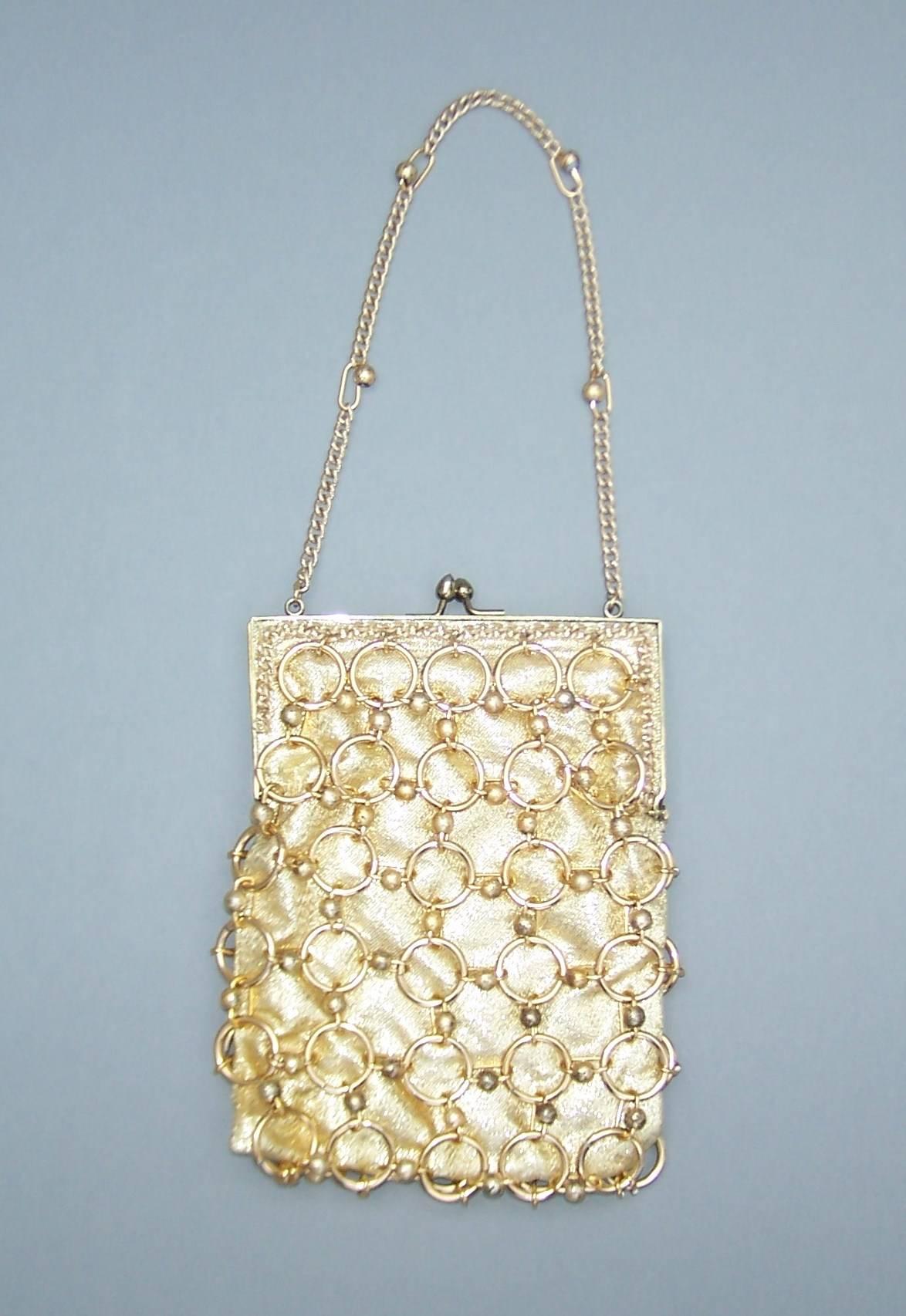 This 1960's Walborg chain mail design emulates the Paco Rabanne space age handbags from the same period.  The handbag is constructed of heavy weight gold lame fabric with a braided metal frame and a jewelry style beaded gold link overlay.  The kiss