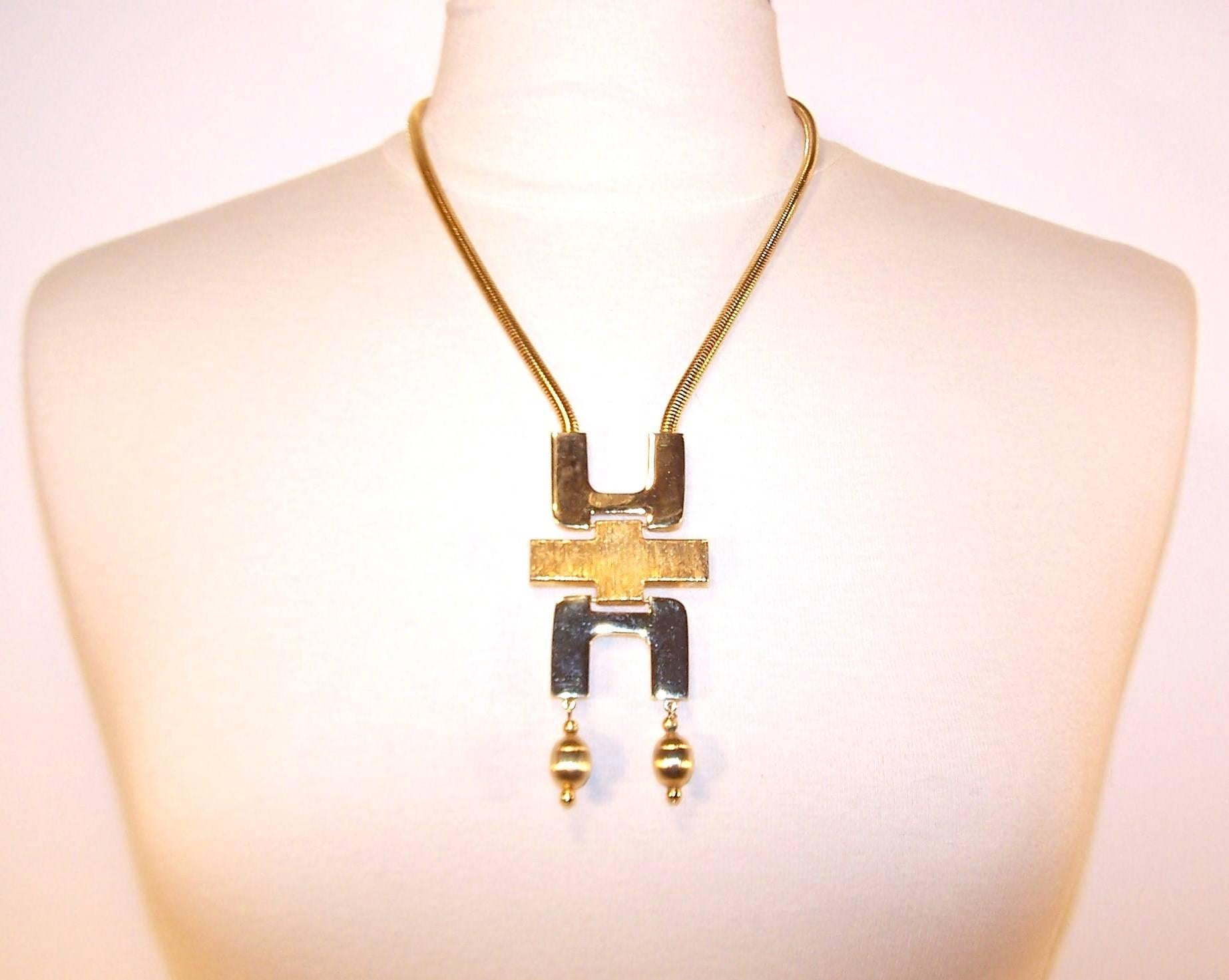 This 1970's Tortolani gold plated necklace is a period perfect mod accessory for a modern wardrobe.  The articulated modernist pendant is suspended from a quality snake style chain with an adjustable hook closure.  The combination of polished and