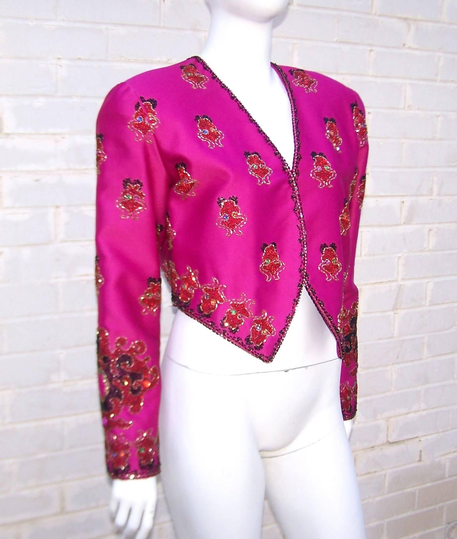 This jacket is unlabeled but it has all the great color combinations of a Christian LaCroix design.  The fuchsia satin is embellished with beaded color combinations of red, green, blue, orange, lilac and outlines in black laced with silver.  It