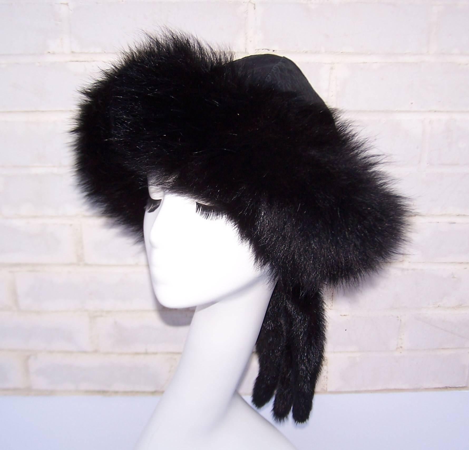 This amazing black fur and leather hat will keep you warm and stylish at the same time.  The body of the hat is a reversible textured leather with satin quilting on the alternate side.  It is trimmed in thick fox fur with fur 'tails' which are