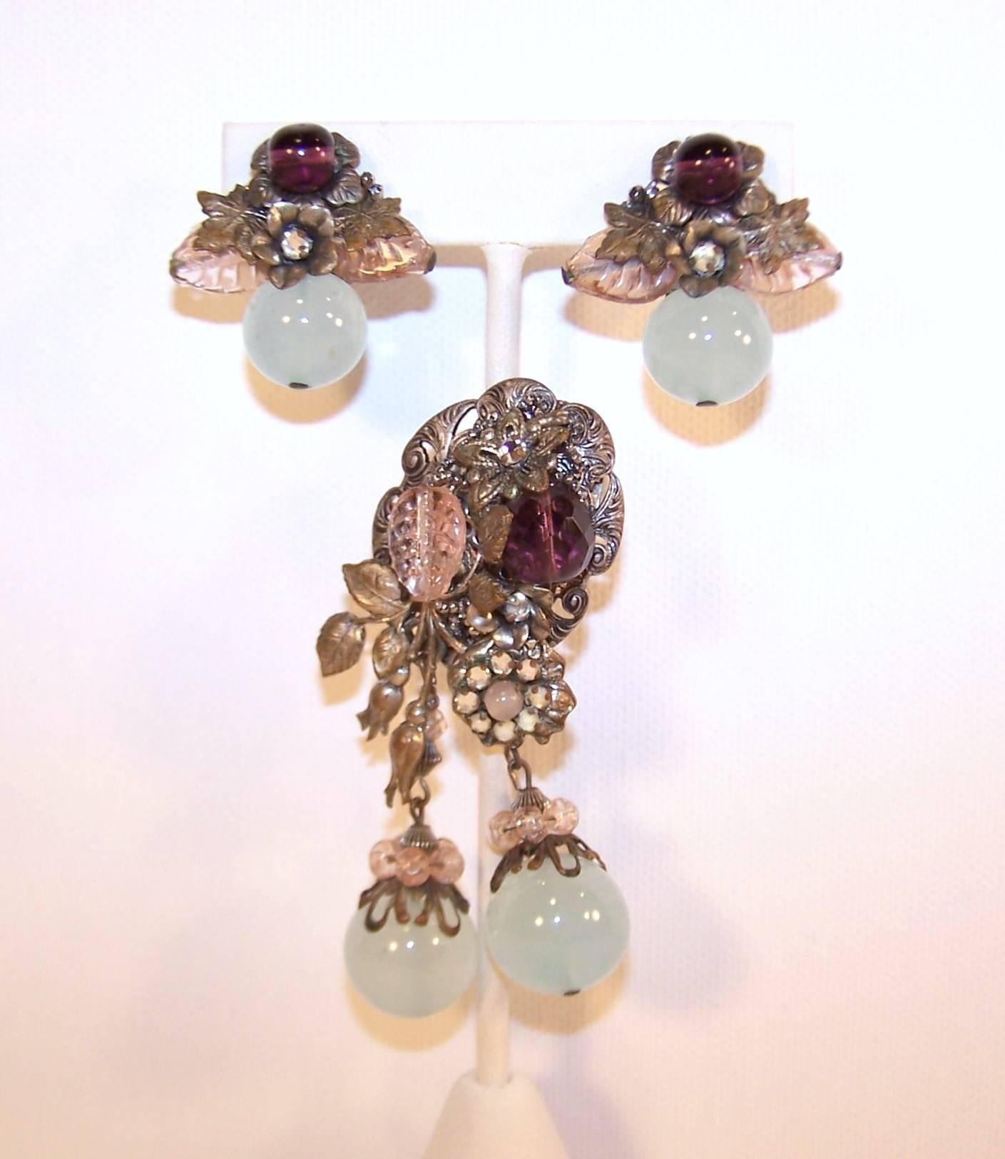 This striking early 1930's set by Miriam Haskell combines the delicate color combination of sea mist, amethyst and flesh-tone pink and a lovely filigreed silver tone metal to create an ethereal accessory which will add vintage charm to a modern