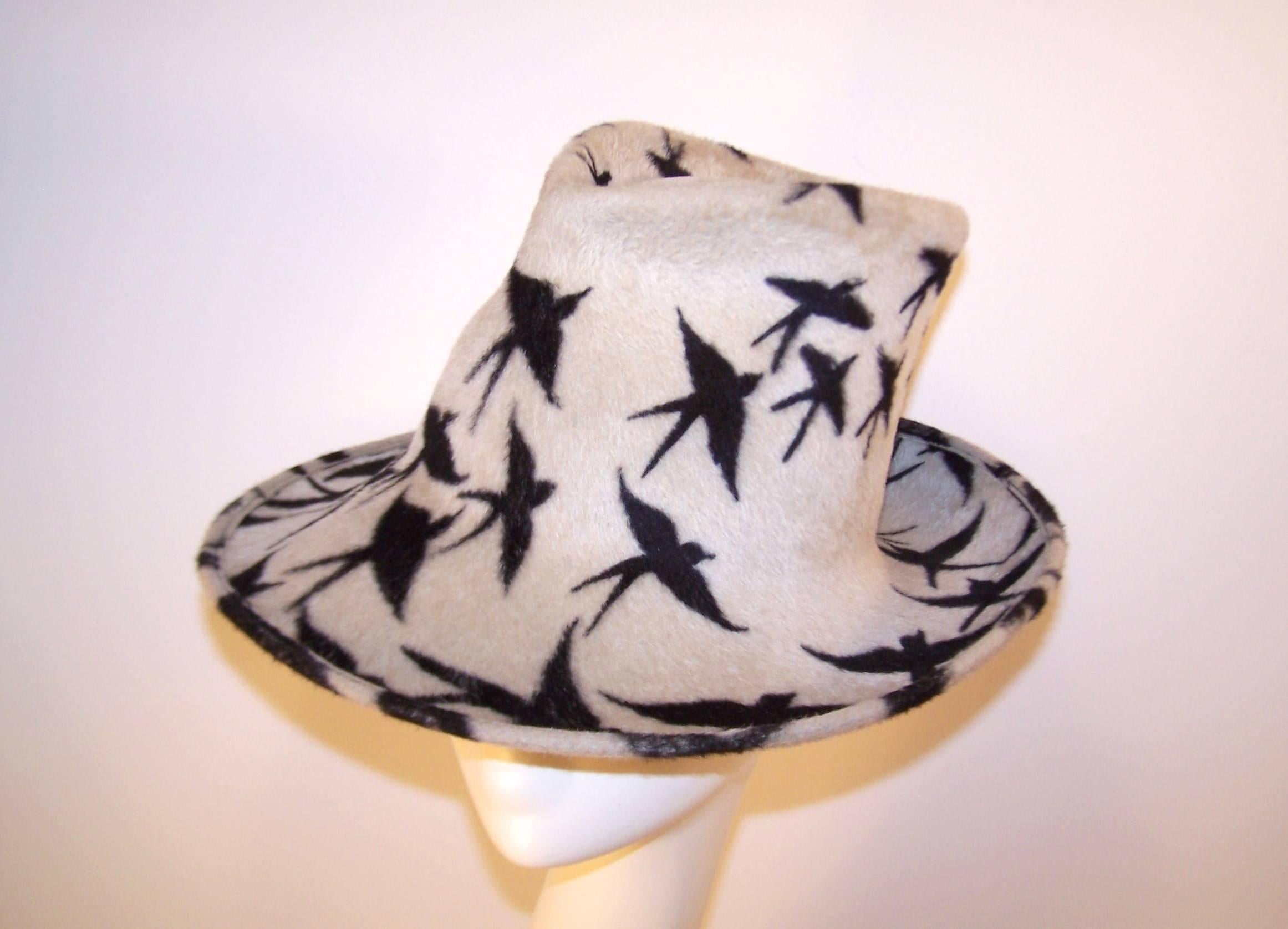 This Philip Treacy hat has an abundance of attitude and style.  The stylized fedora shape is upturned, downturned and pinched for the ultimate fashionable effect.  The soft wool dove gray body is artistically enhanced with a black bird motif.  In