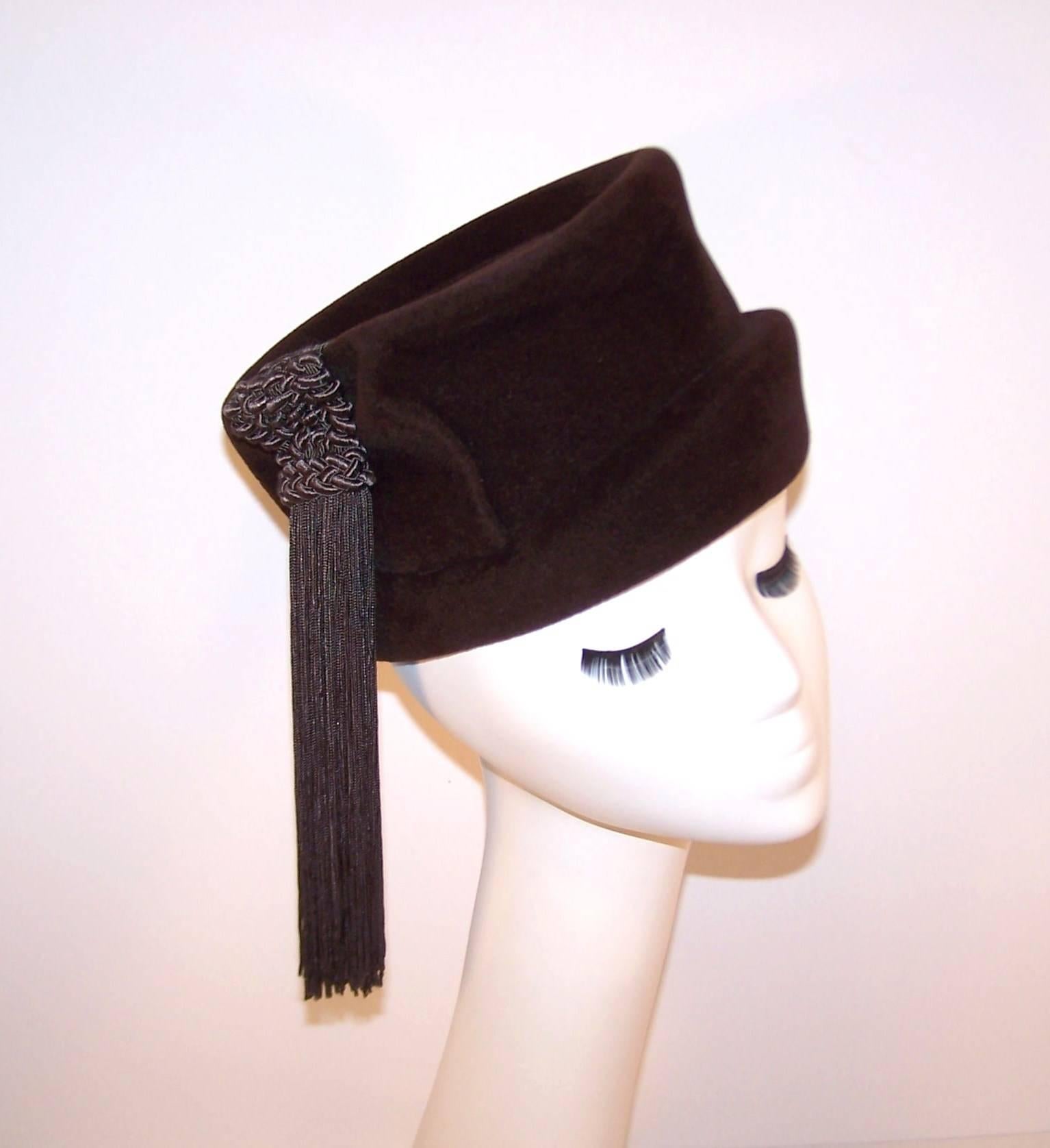 This Marion Valle hat is reminiscent of a ladies' fox hunting style hat from the same era.  The dark chocolate wool body is expertly crimped with a shallow brim and a braided silk tassel decoration adding visual interest and movement.  The hat form