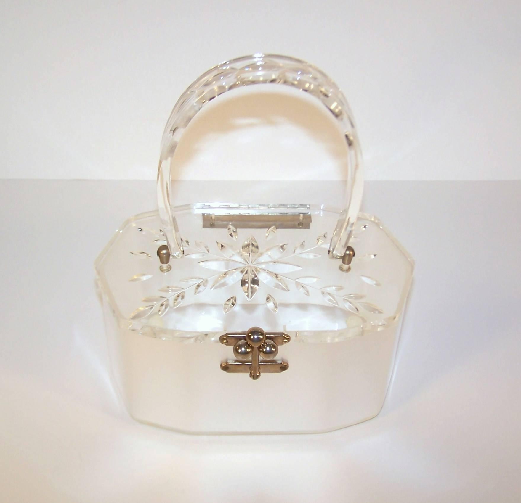 Perfect for a modern day Cinderella!  This classic 1950's lucite handbag has a hand carved clear lid and handle with a pearly white sateen body.  The 10-sided boxy shape has a three ball closure that securely snaps in place.  Fashionable ladies in