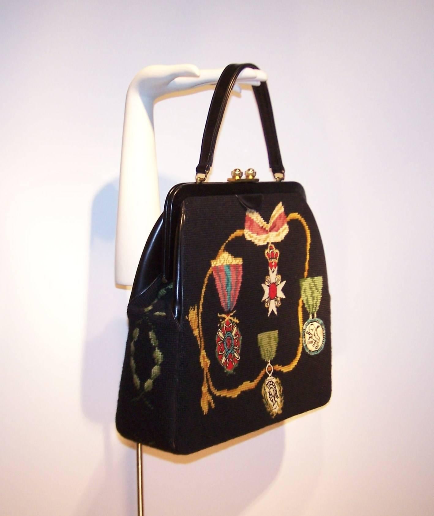 Faboo!  This 1950's trompe l'oeil needlepoint handbag is the be all end all.  The black background is decorated with needle work (including petit point) depicting medals and badges of honor in vibrant royal colors.  The back side depicts a crown and