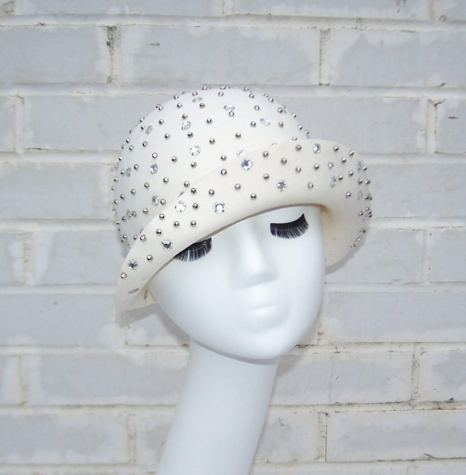 Adolfo's 1970's version of a 1920's flapper hat with the elements of a close fitting cloche and the addition of disco ready silver tone studs and rhinestone embellishments.  The ivory white wool felt body is in excellent condition with every sparkly