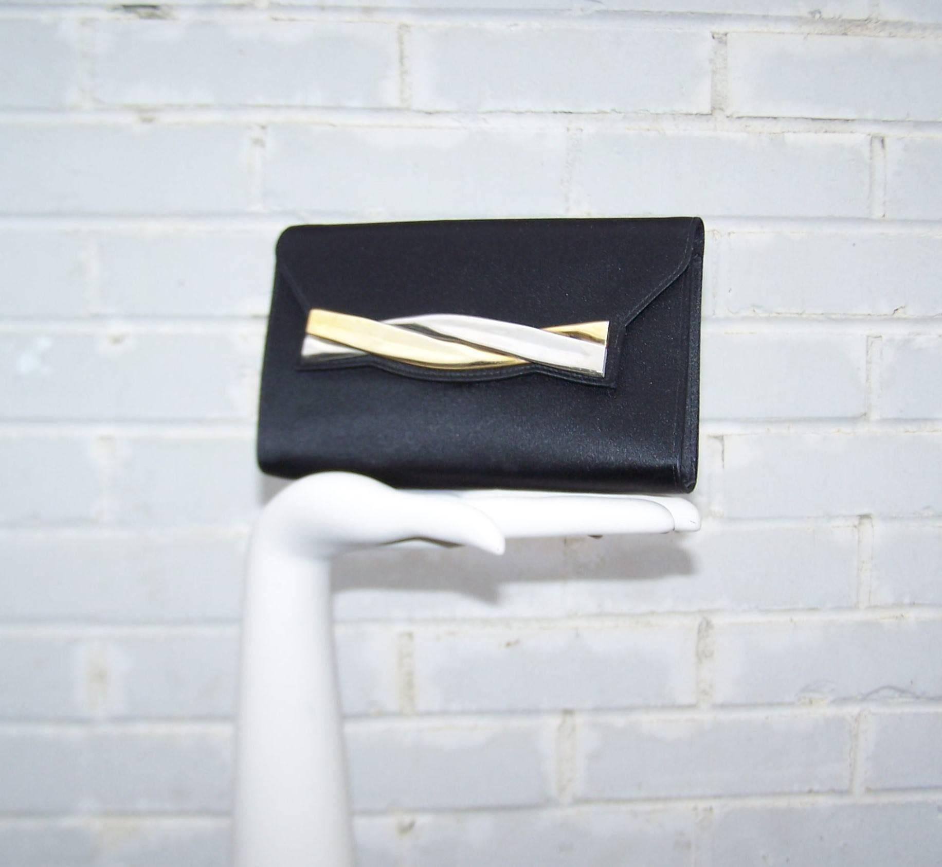 Perfect little evening clutch handbag by Salvatore Ferragamo.  The black satin body is offset by modernist gold and silver tone metal decoration which adds visual interest to the simple design.  The front flap snap closure opens to reveal an