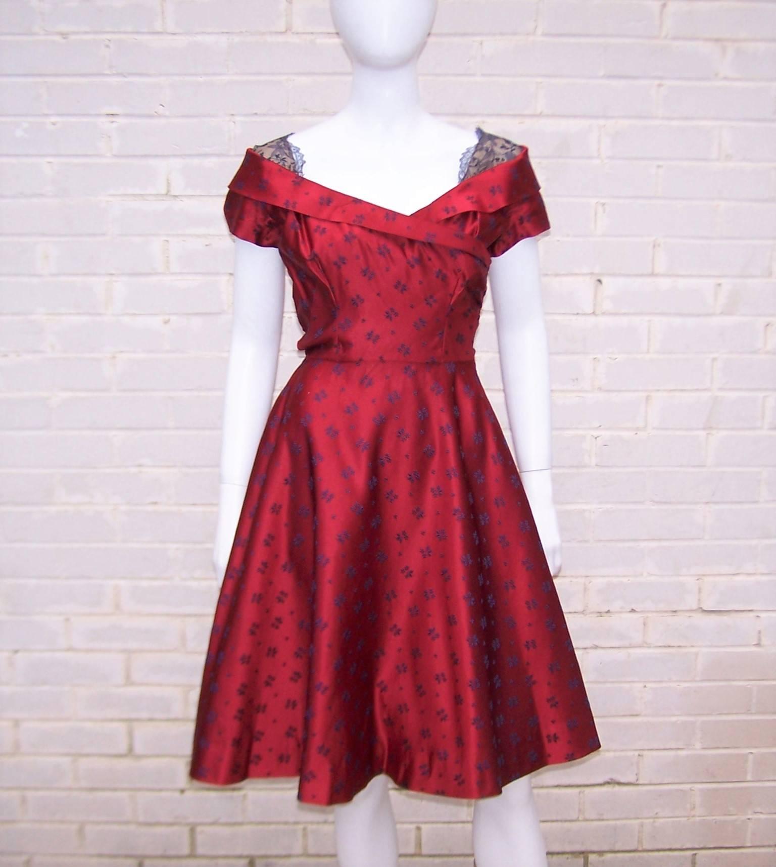 This early Adele Simpson design is the epitome of a fun party dress.  The cherry red satin fabric is accented with navy blue flowers and provides the right amount of stiff structure to create both a cinched and flared silhouette.  The dress zips and