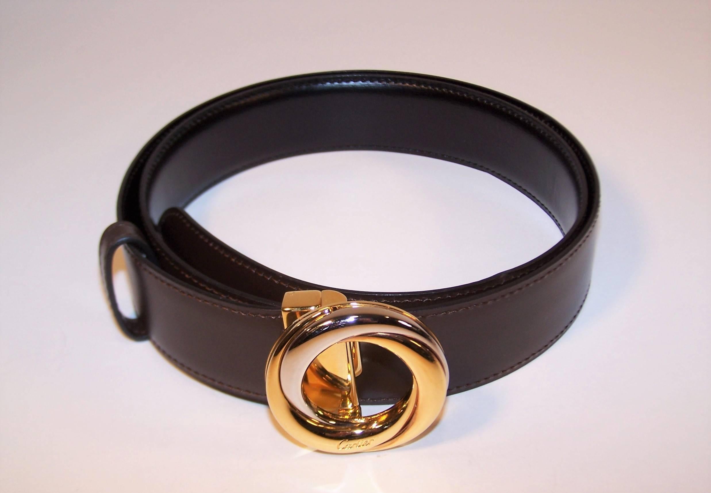 This classic 'Trinity' belt from Cartier is a wonderful wardrobe essential.  The 1.63" diameter silver and gold plated buckle is designed to clip off with a hinged lever allowing an easy conversion to the reversible leather belt from a dark