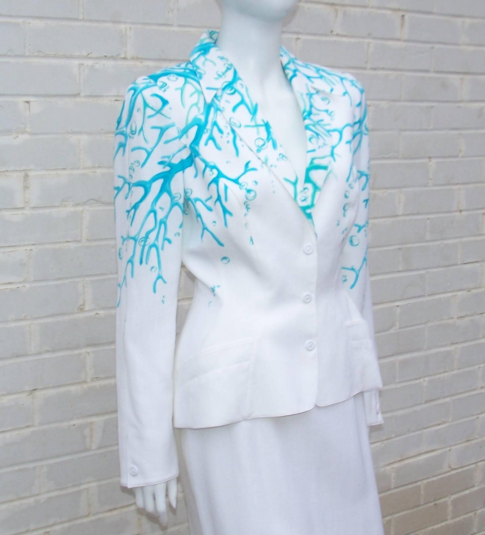 Thierry Mugler creates a tropical vibe with this crisp white linen blend suit decorated with aqua coral motif laced with a hint of sea foam green.  The classic Mugler wasp waist jacket snaps at the front with fabric covered buttons and stylish