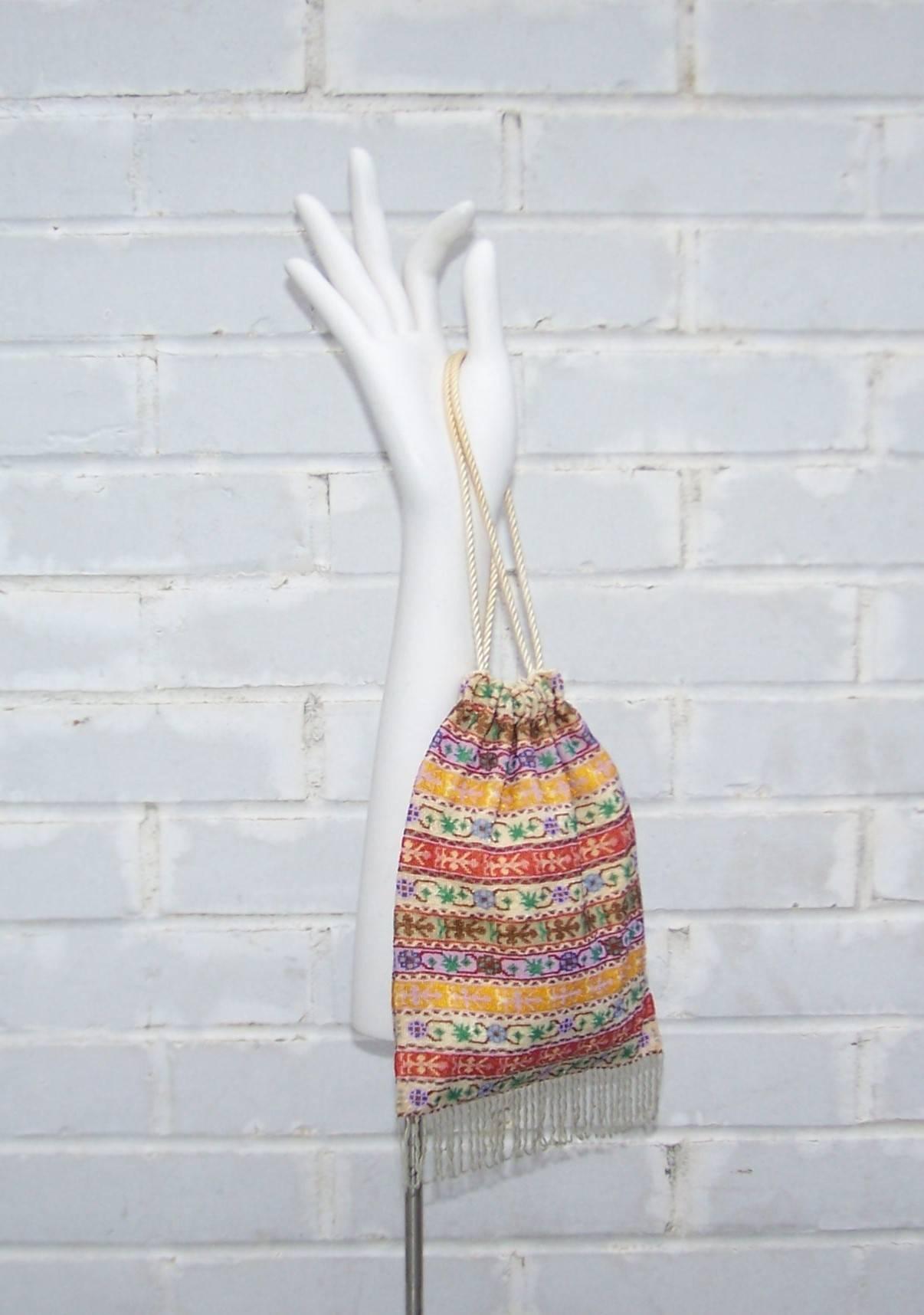 This handbag is reminiscent of the micro beaded drawstring handbags of the early 1900's but with a vibrant 1960's visual twist.  The intricate striped floral design is colorfully beaded with glass beads so tiny that they are best appreciated with a