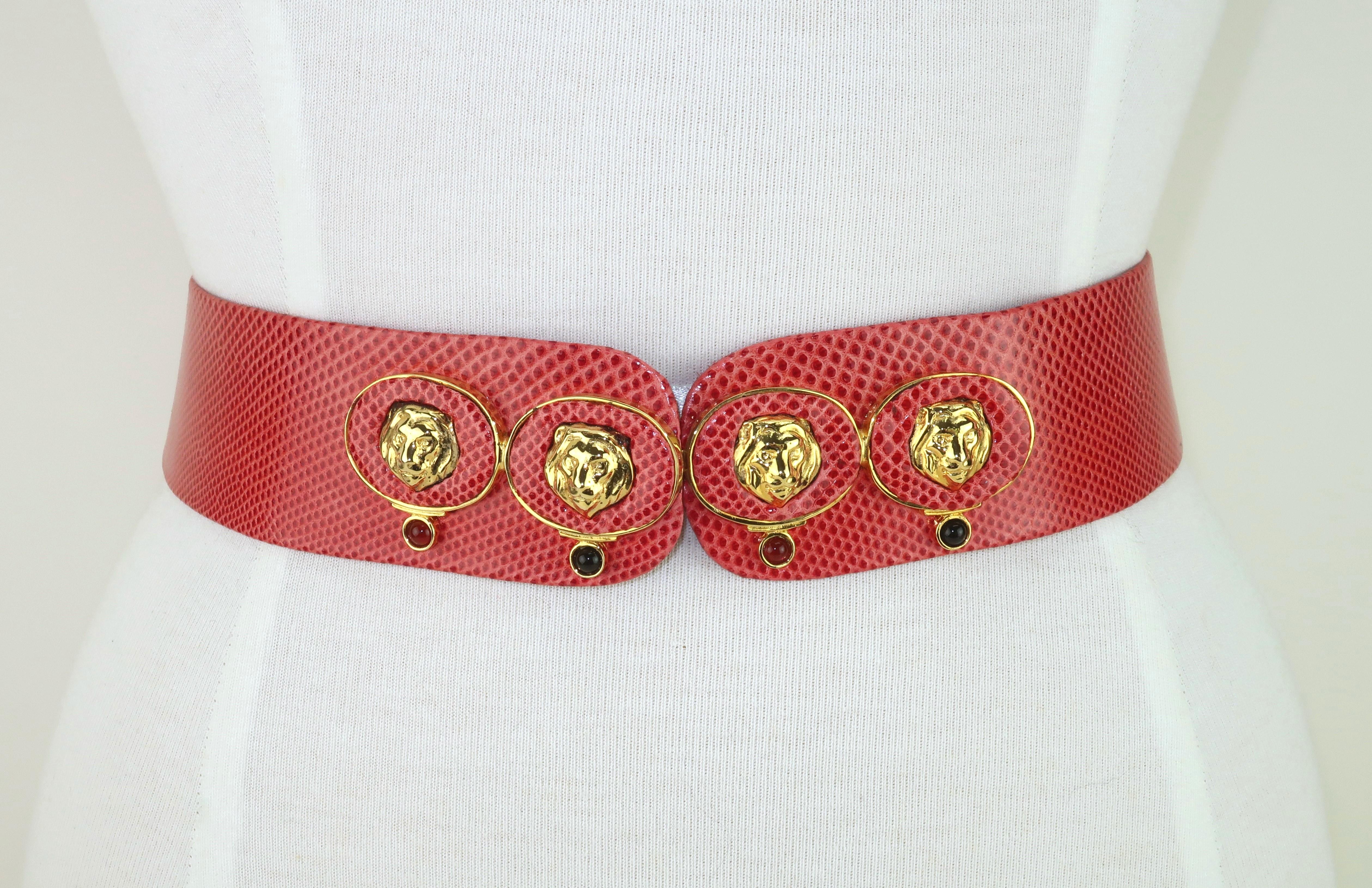 Cintura regolabile Judith Leiber del 1980 in pelle di lucertola rosso corallo con medaglioni di leone placcati in oro e pietre cabochon.  La cintura si aggancia sul davanti creando un design senza cuciture.  Si regola facilmente facendo scorrere due