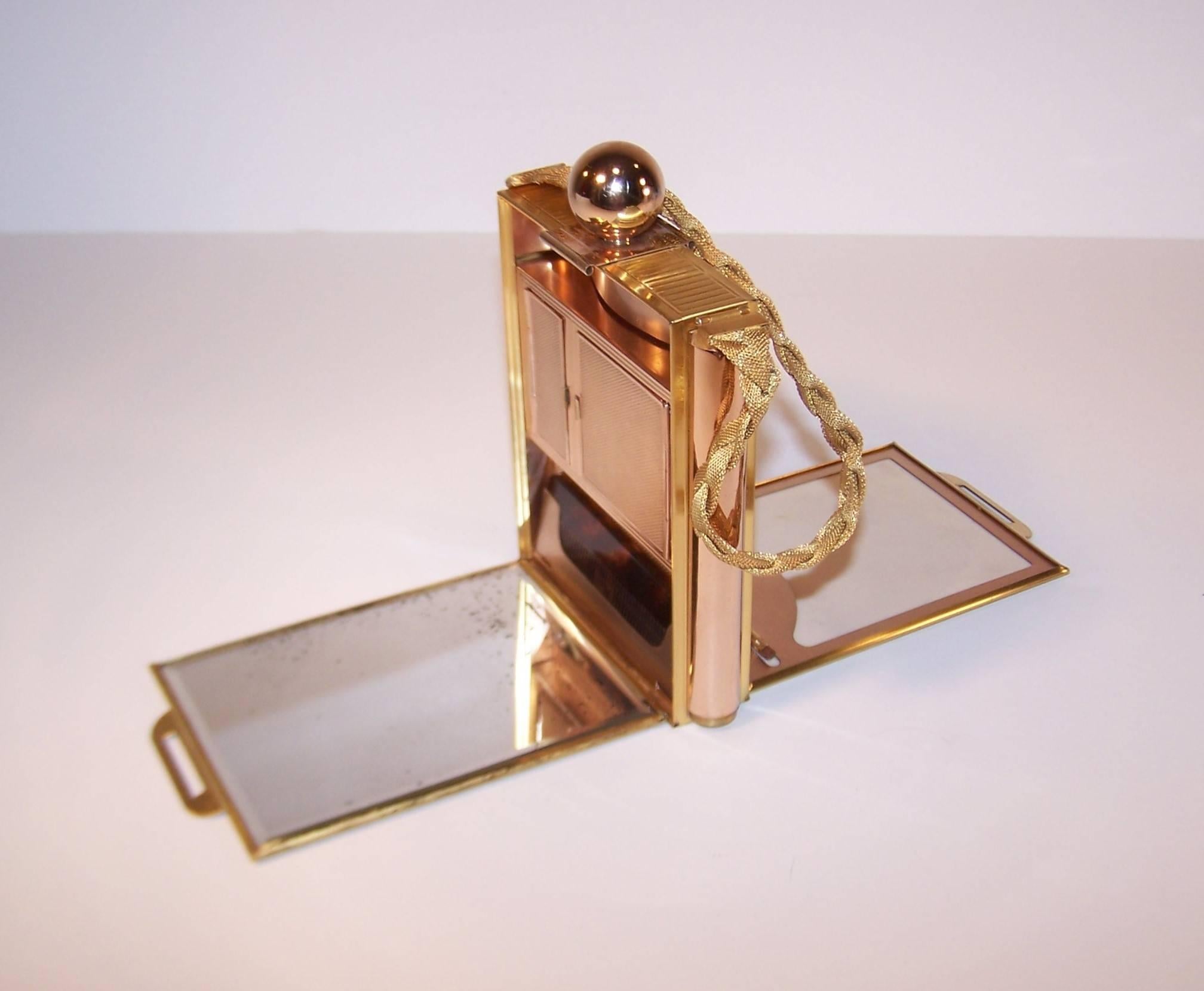 Much like chantelaines, elaborate mirrored compacts are feminine gadgets of a bygone era.  This tri color metal example from the Evans Co. has the appearance of a stylized feminine flask but opens to reveal compartments for everything from face