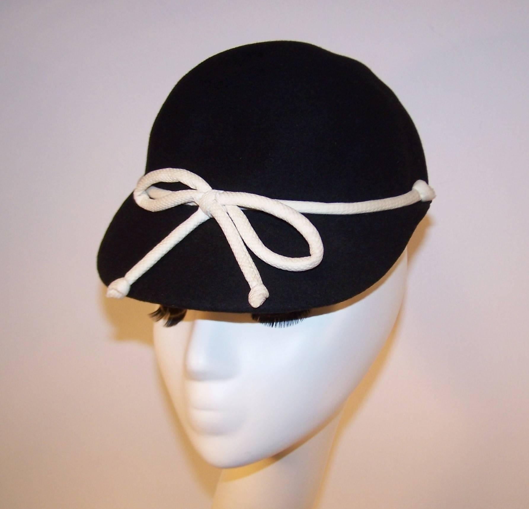 This adorable 1960's topper by Henry Pollak has a sporty style somewhere between a riding hat and an old fashioned ball cap.  The black wool body is embellished with an off white cotton pique bow lending the hat a Springtime vibe perfect for warm