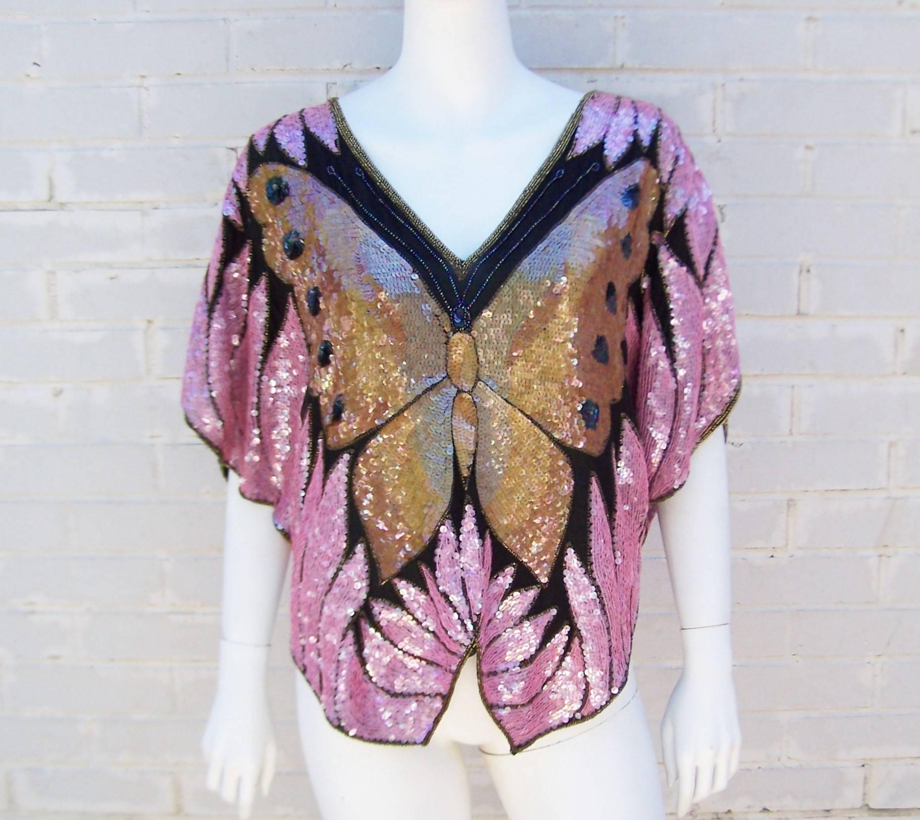 Transform yourself with a sequin touch!  This C.1980 pullover top by Saks Fifth Avenue is an amazing piece of wearable art.  The lined gauzy black fabric background serves as a canvas for the well placed pink, midnight blue and golden sequins.  Gold