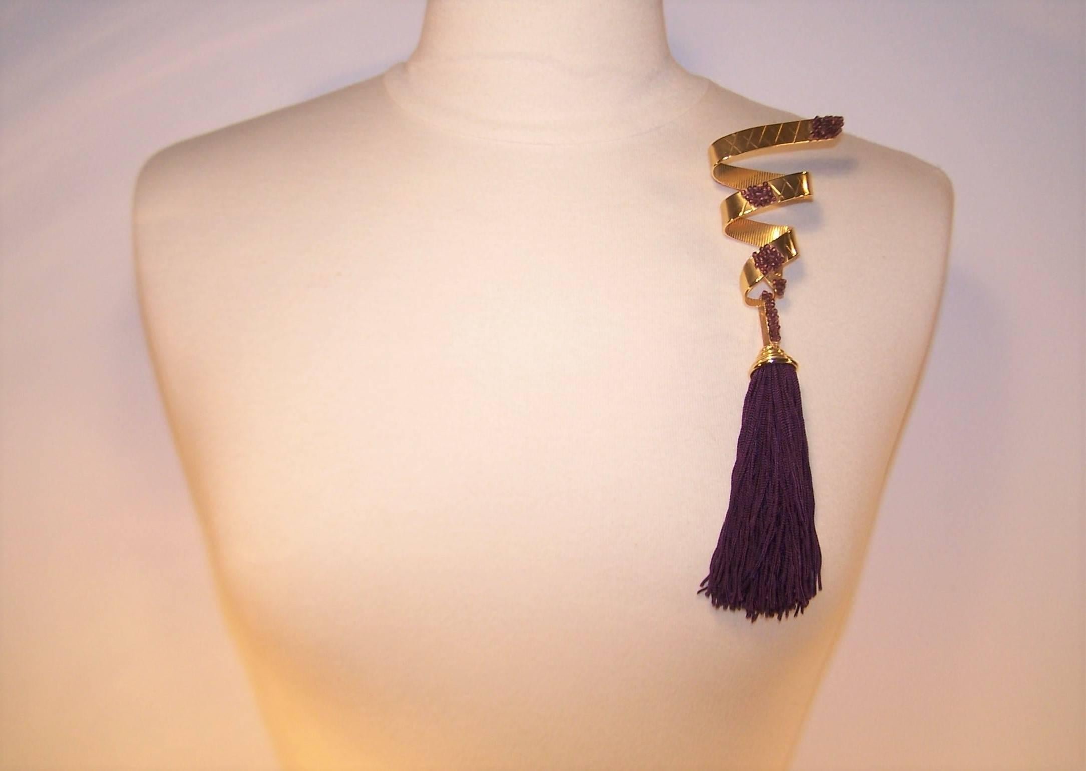 A large statement brooch can be the perfect accessory for an outfit.  This fun Italian piece by Spazio features gold tone metal detailed with cross hatching and embellished with purple beading and an articulated silk tassel.  It measures a total of