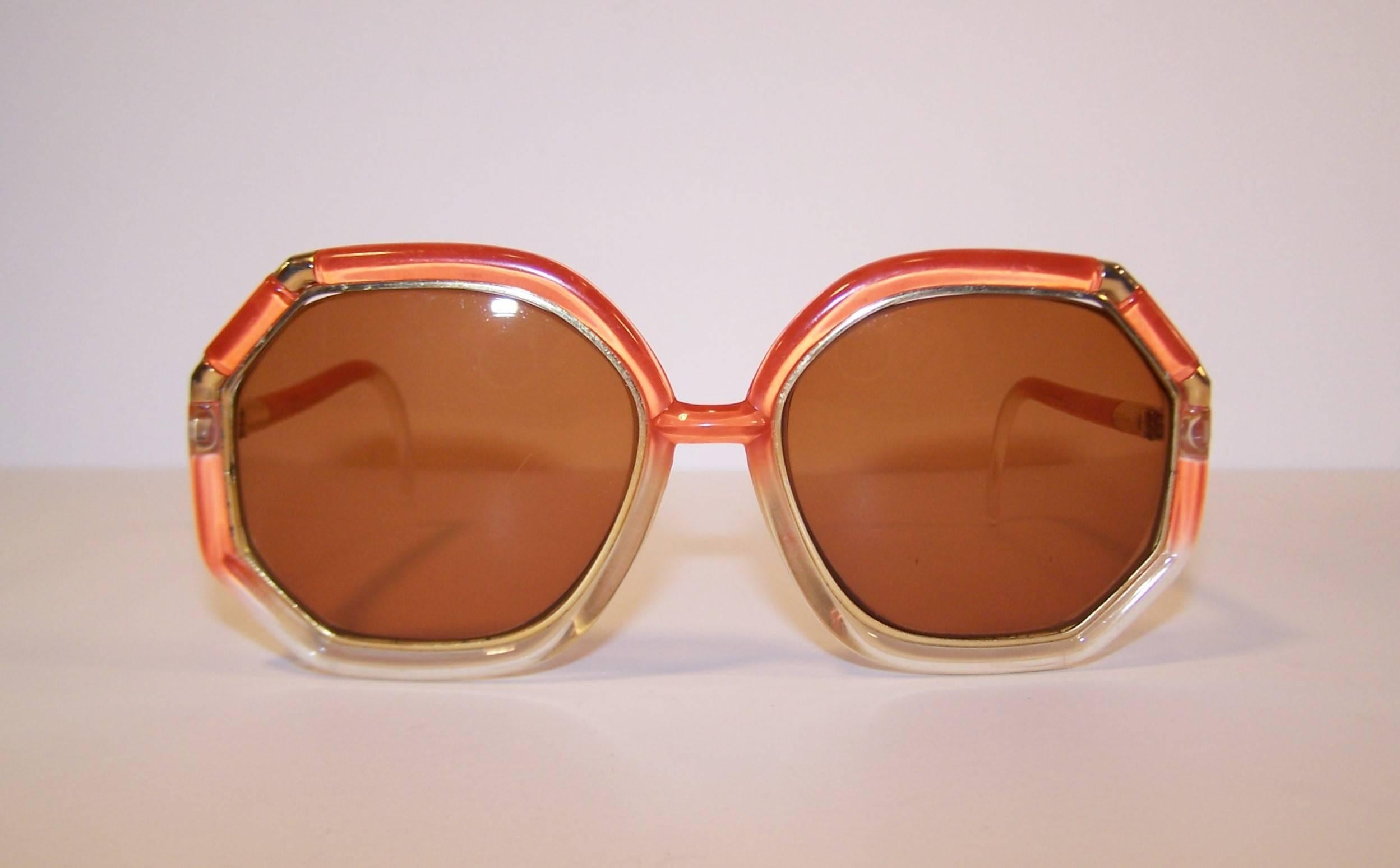 1970's Ted Lapidus sunglasses are the epitome of period perfect pop mod style.  These translucent tangerine orange shades fade from color to clear providing a gradient design with amber colored lenses and gold metal embellishments.  The tubular