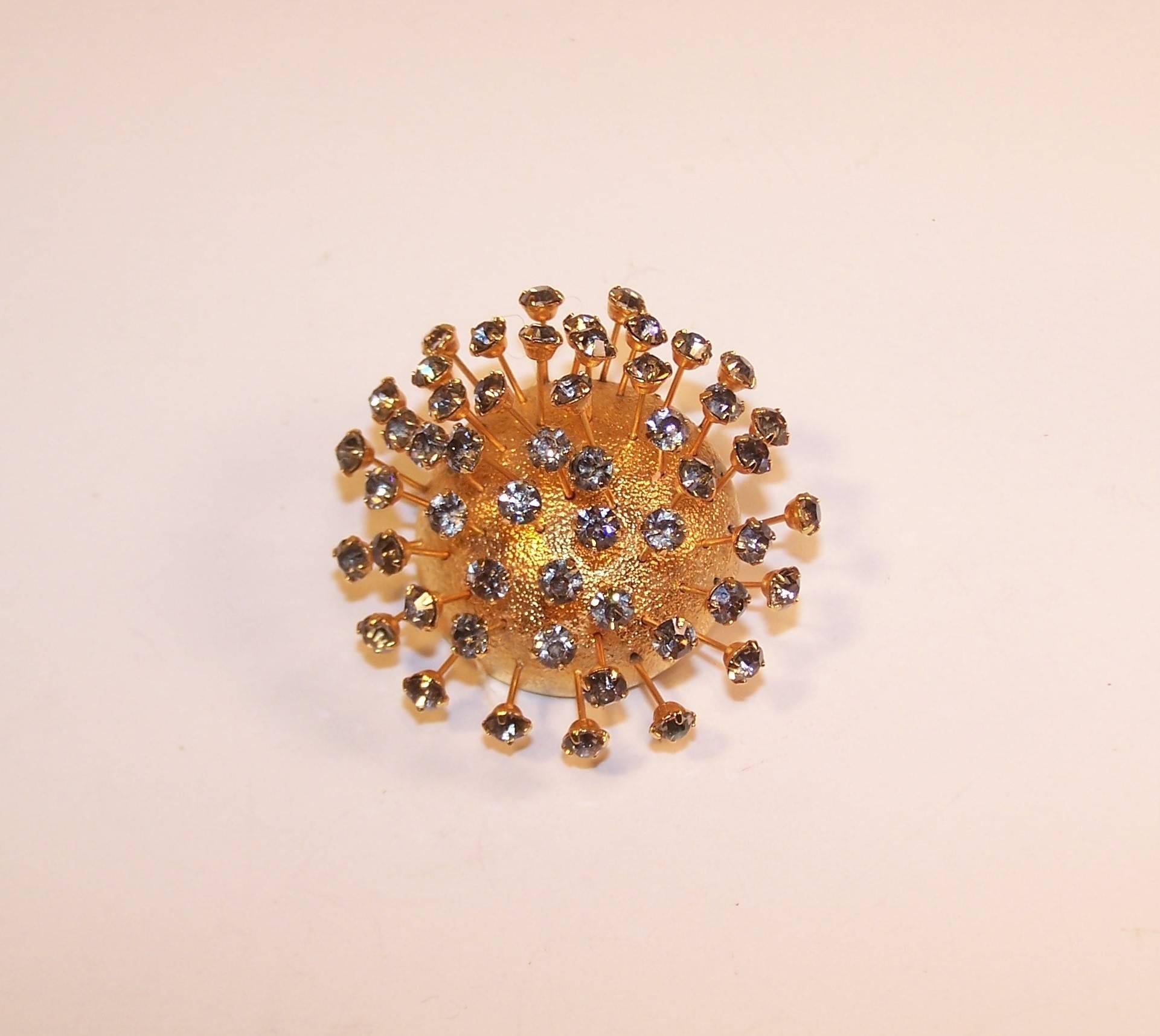 This sputnik style brooch by Corocraft of the Coro Jewelry Company has space age style with timeless elegance.  The gold tone metal base is textured to serve as the perfect background for rhinestone tipped rods that 'tremble' to create movement and