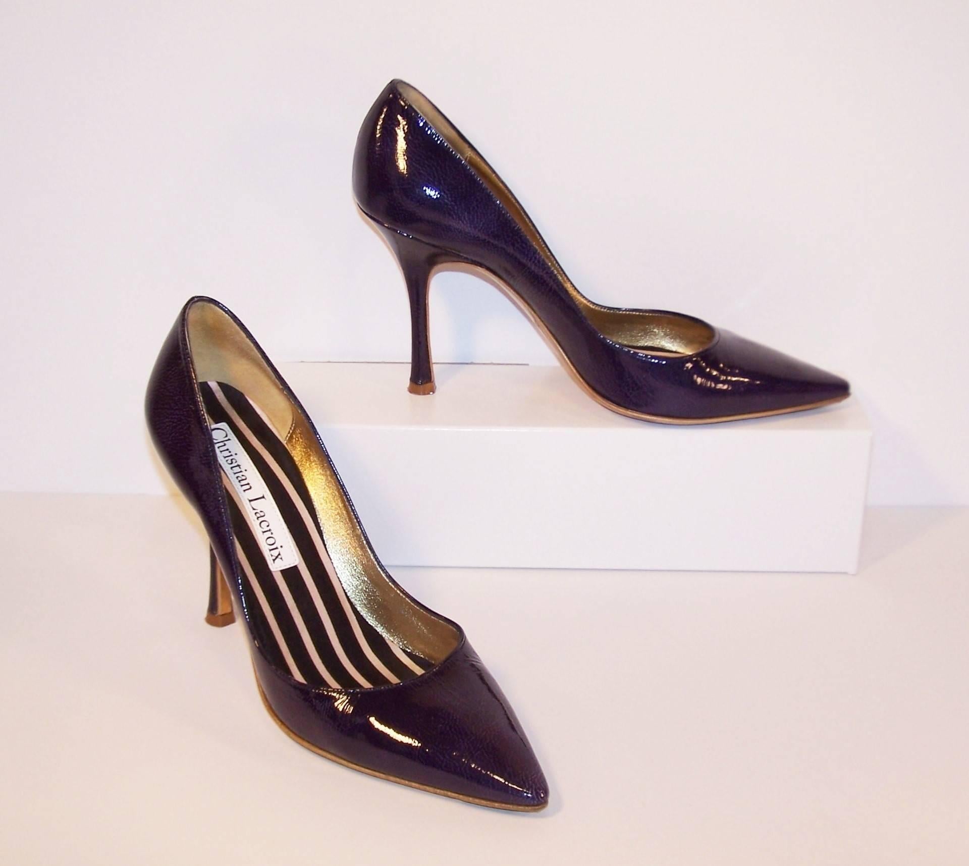 These stiletto shoes have all the classicism of a 1950's silhouette with a dash of Christian Lacroix's modern magic in the form of a unique mottled surface creating a subtle purple undertone to the blue laminated leather.  Add a striped satin foot